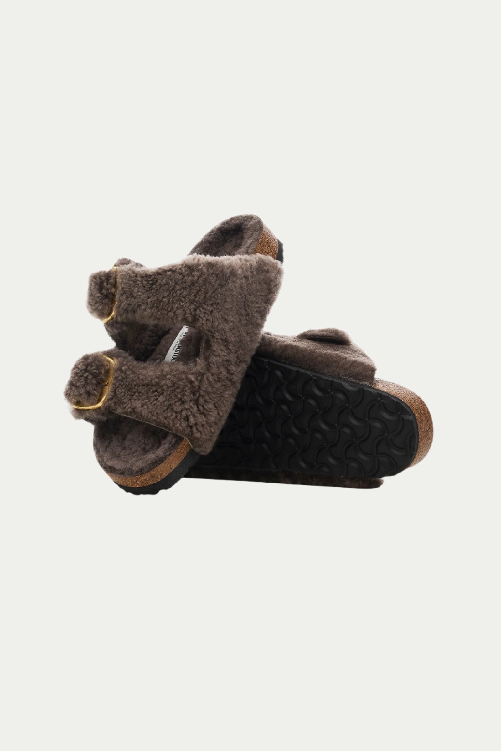 A pair of Womens Arizona Big Buckle Teddy Grey Birkenstock Sandals with black textured soles are stacked on top of each other against a plain white background.