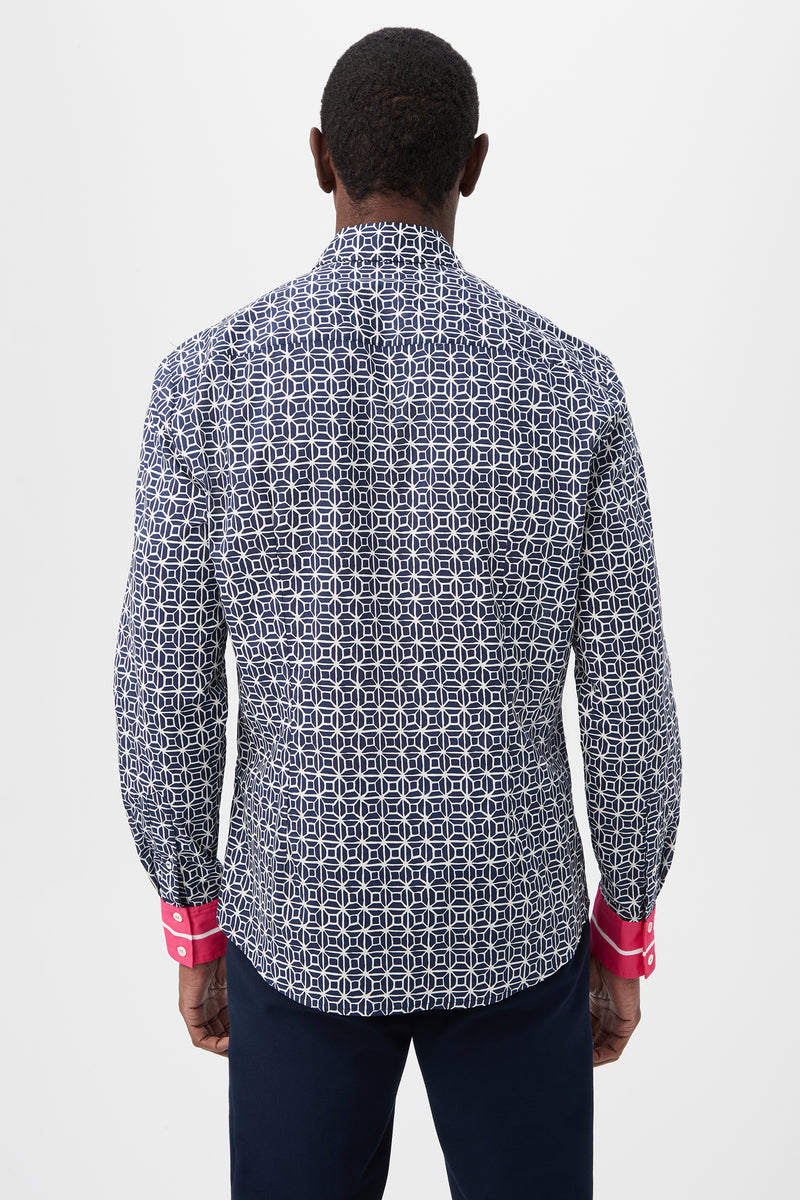 A man stands facing away, wearing the Aaron 2 Slim Long-Sleeve Shirt in navy blue and white with bright pink cuffs and dark pants, set against a plain white background.