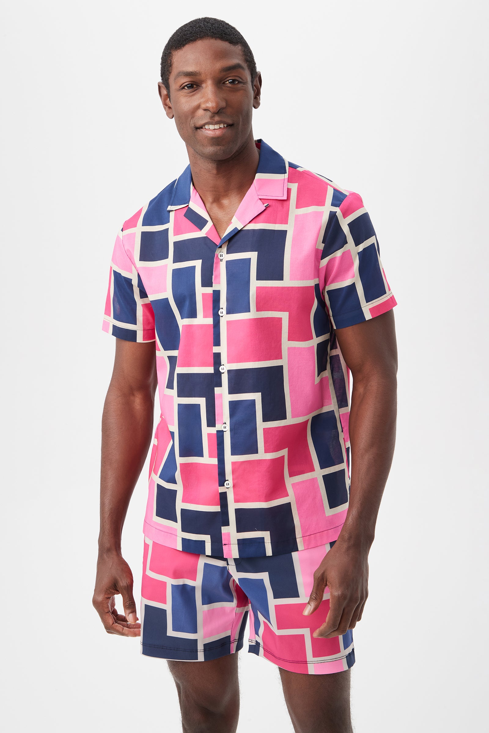A man smiles wearing the Felix Camp Shirt - Block Party in Multi, a matching short-sleeve set with a bold geometric pattern, standing against a plain white background.