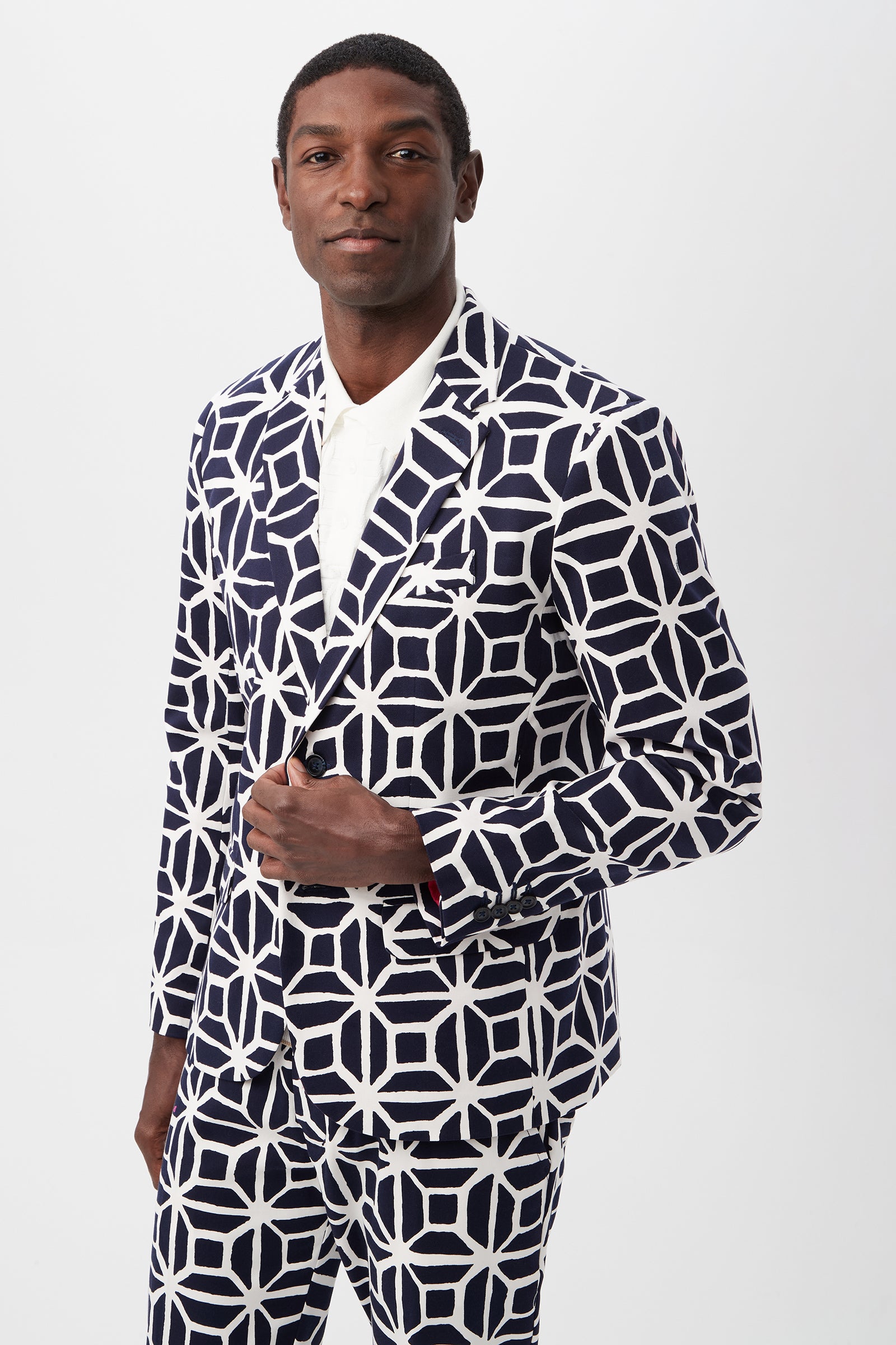A man wearing the Thurston Blazer - Durell Herringbone in indigo over a white shirt stands against a plain white background, looking confidently at the camera.