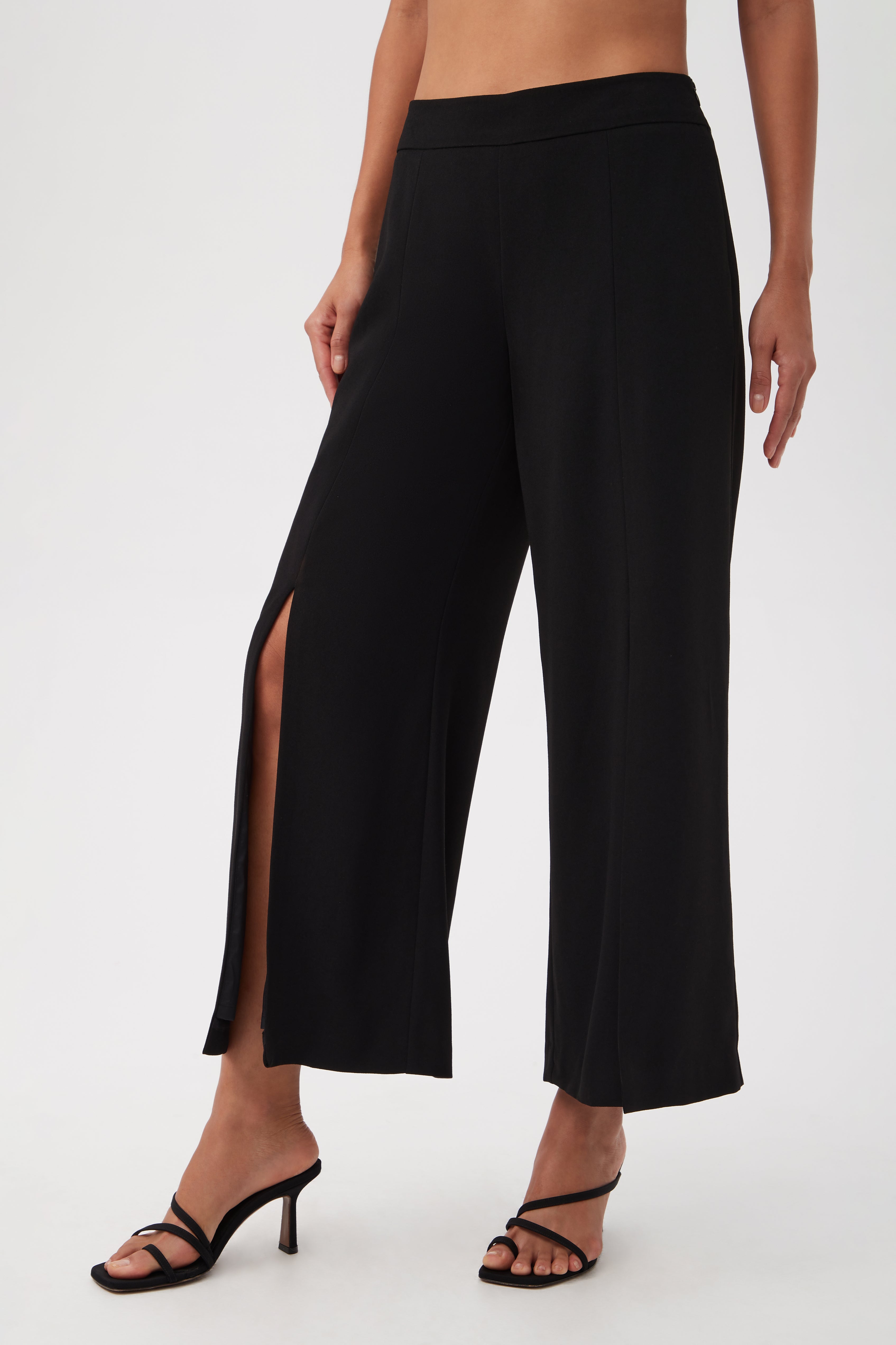 A person wearing Davon Cropped Wide-Leg Pants With Front Slits and black heeled sandals, shown from waist to feet against a plain background.