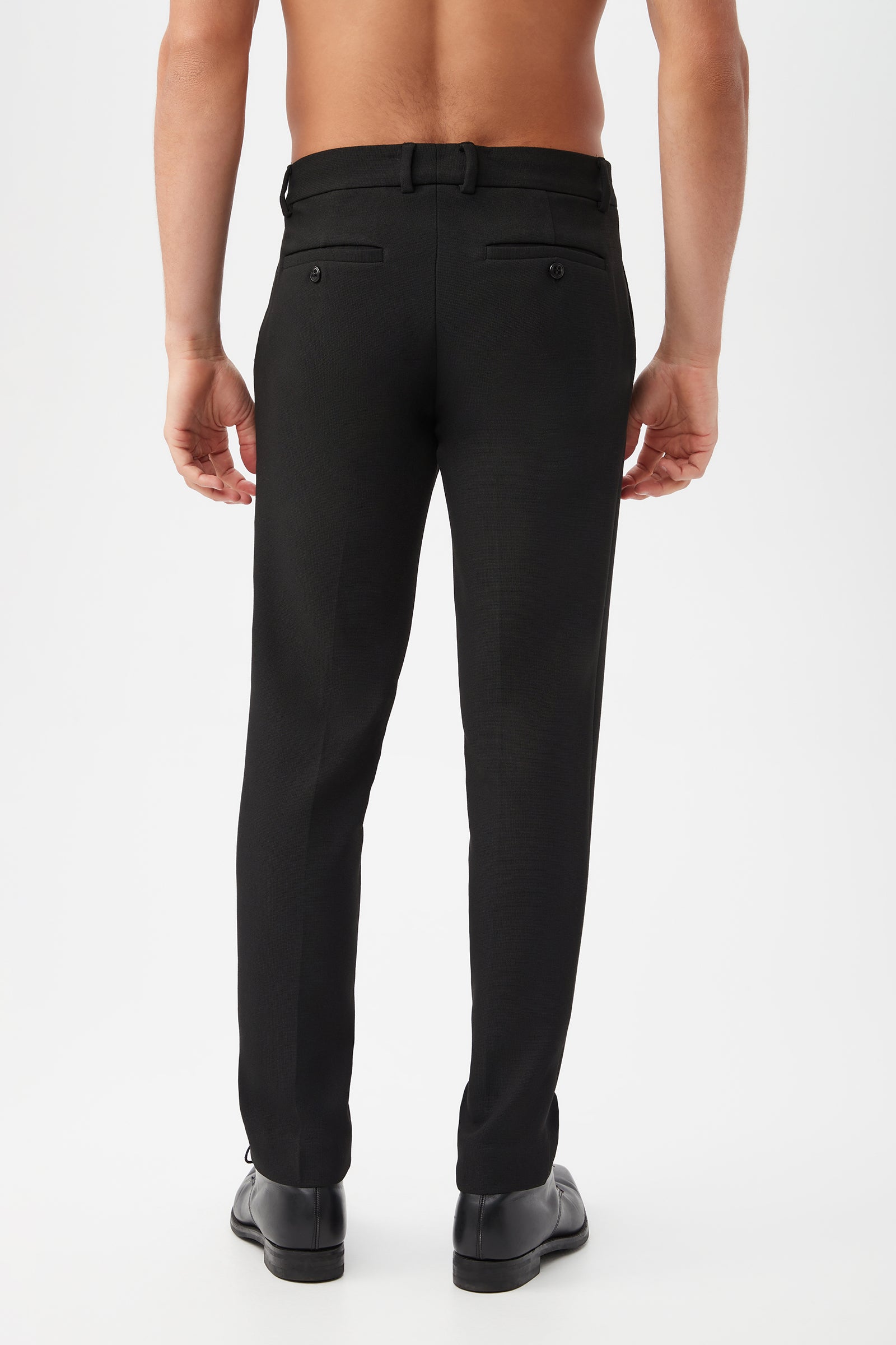 A shirtless man, seen from behind, models the Clyde Slim Trouser - Hi-Line Suiting with dress shoes against a plain white background.