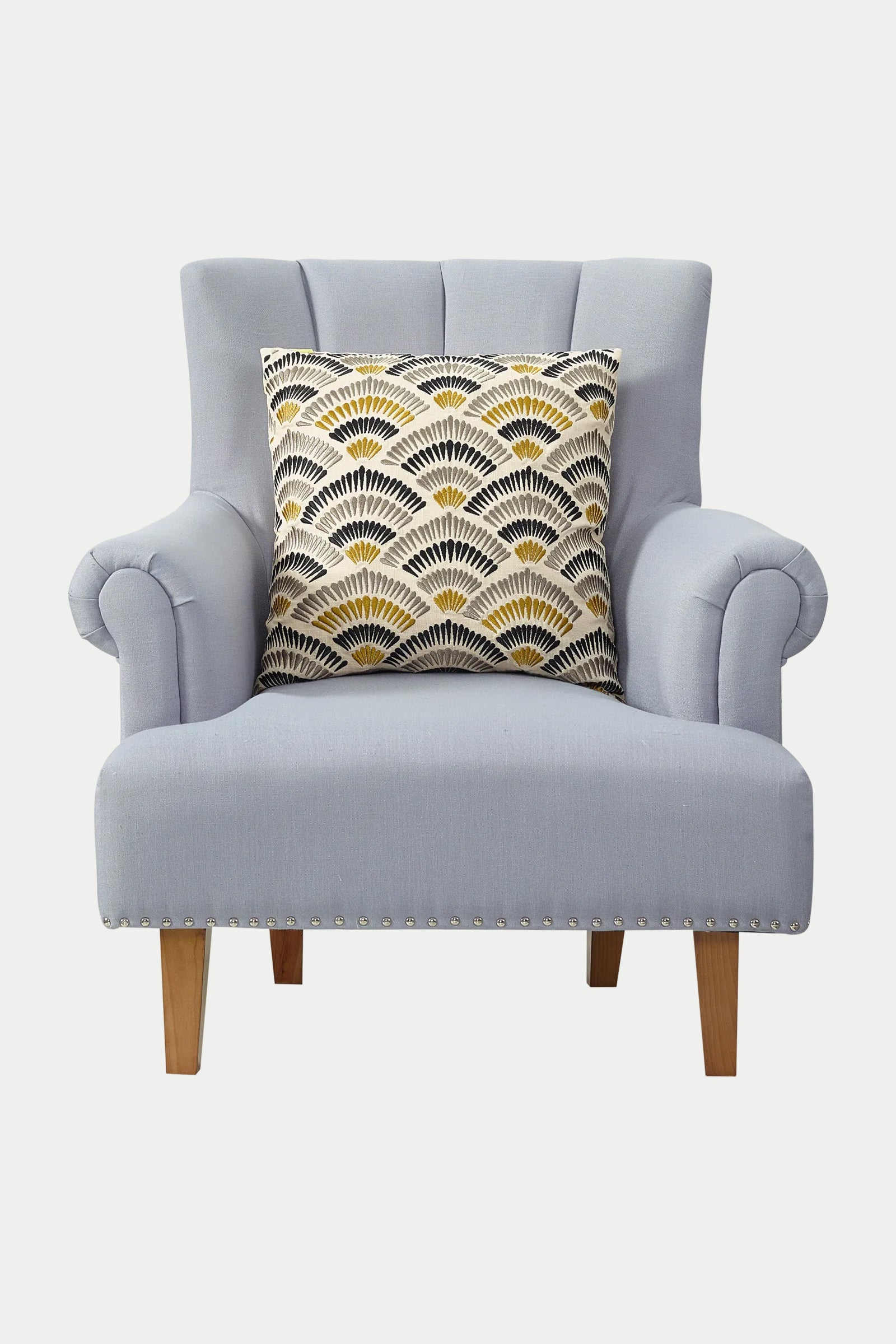 A light blue upholstered armchair with wooden legs, featuring the Pasadena Embroidered Euro Throw Pillow in gold, is placed against a white background.
