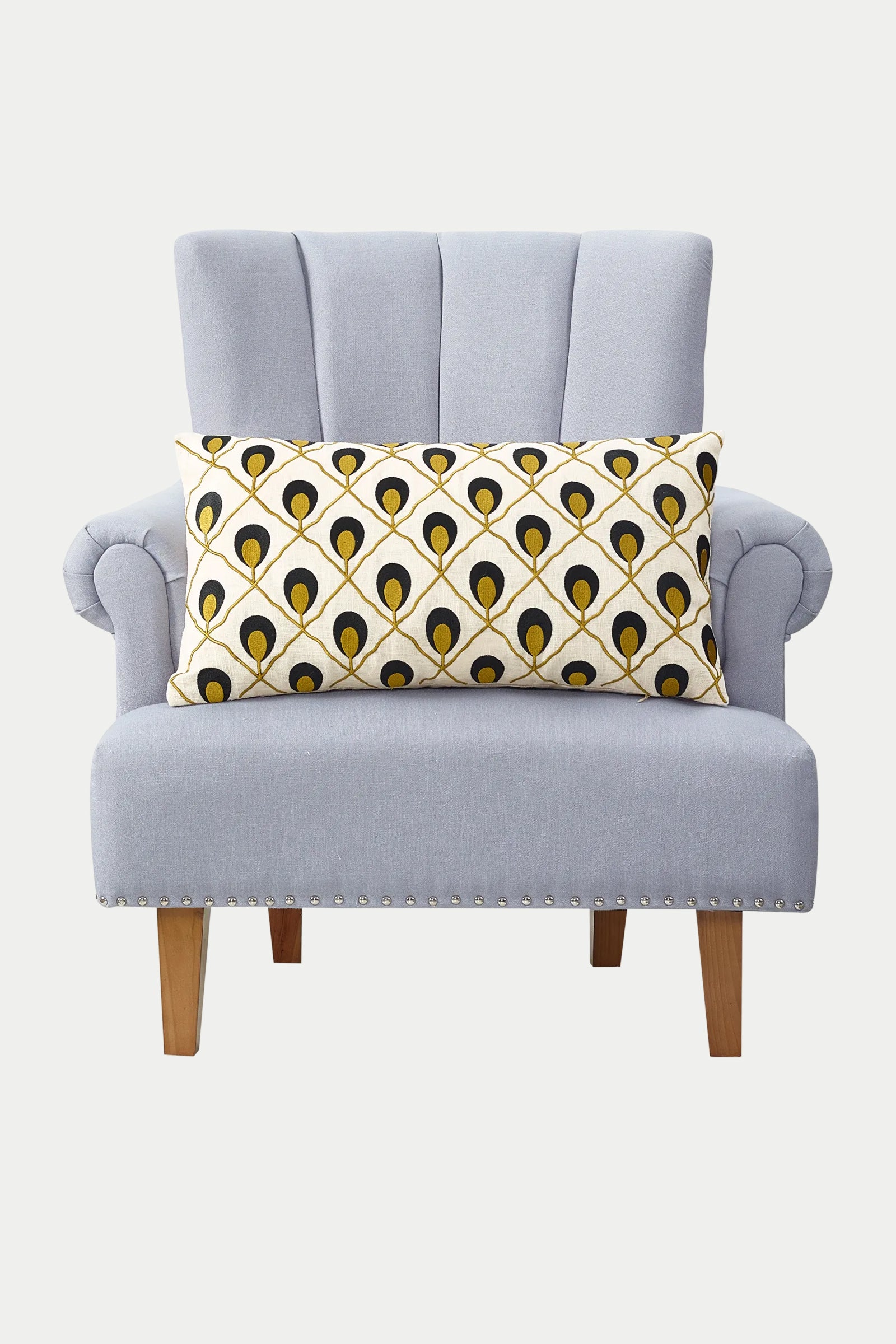 A light gray upholstered armchair with wooden legs and a rectangular Roseville Embroidered Throw Pillow in gold.