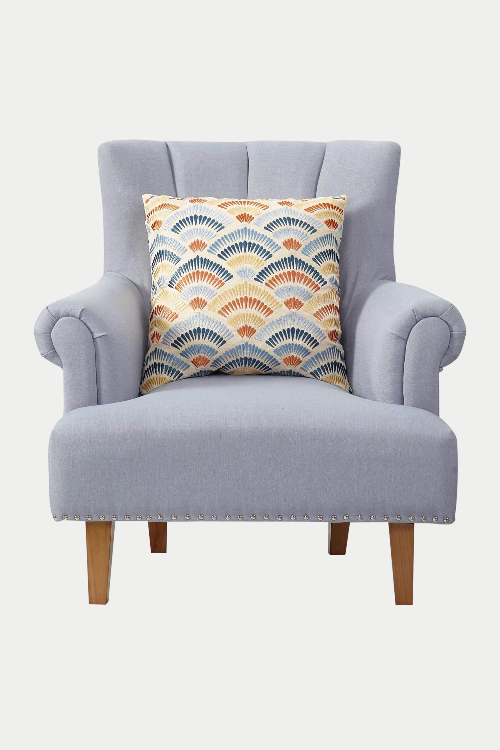 A light gray upholstered armchair with wooden legs, featuring the Pasadena Embroidered Euro Throw Pillow - Terra with a colorful geometric fan pattern in blue, orange, and yellow tones placed on the seat.
