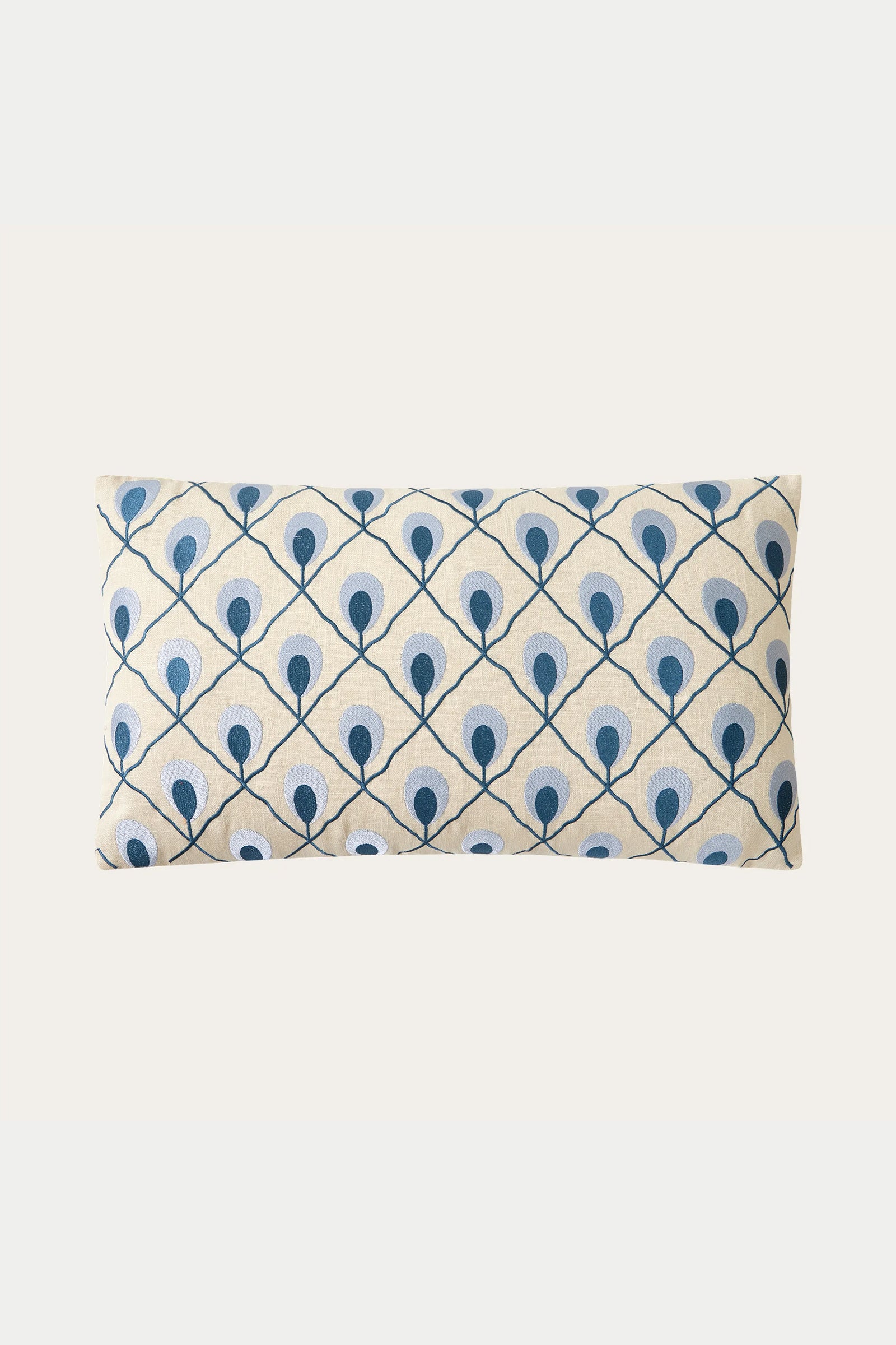 The Roseville Embroidered Throw Pillow - Terra is rectangular with a cream background and features a grid of blue and light blue peacock feather-inspired patterns.