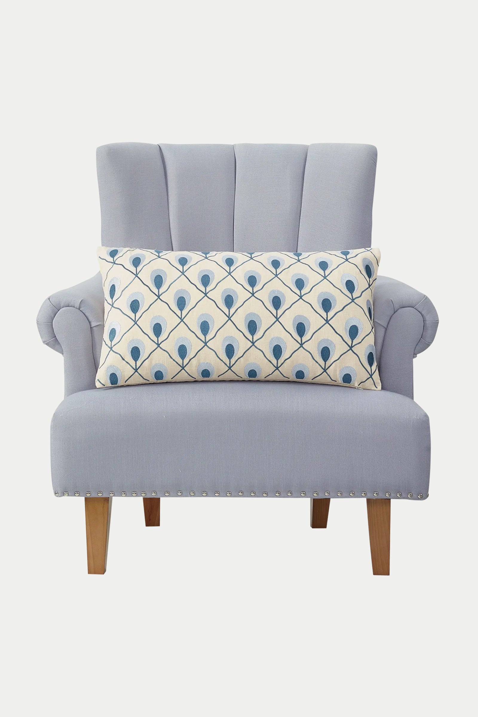 A light blue upholstered armchair with wooden legs, featuring the Roseville Embroidered Throw Pillow - Terra, showcasing a rectangular cushion with an embroidered design.