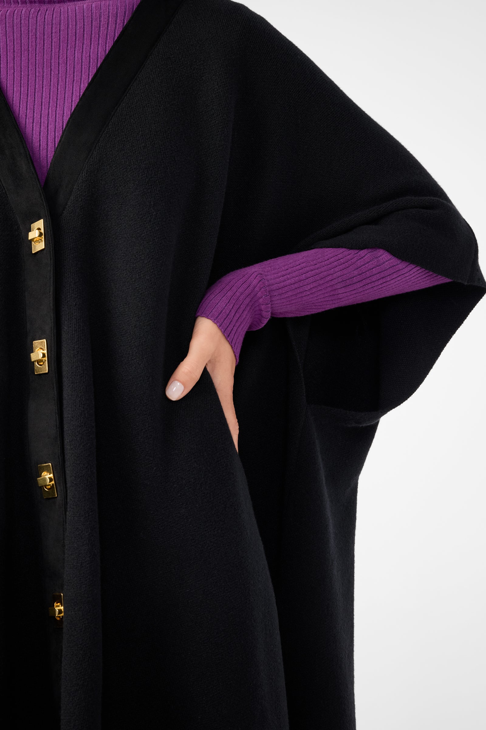 A person wearing the Sapphire Poncho with one hand placed at their waist; only part of the upper body is visible.