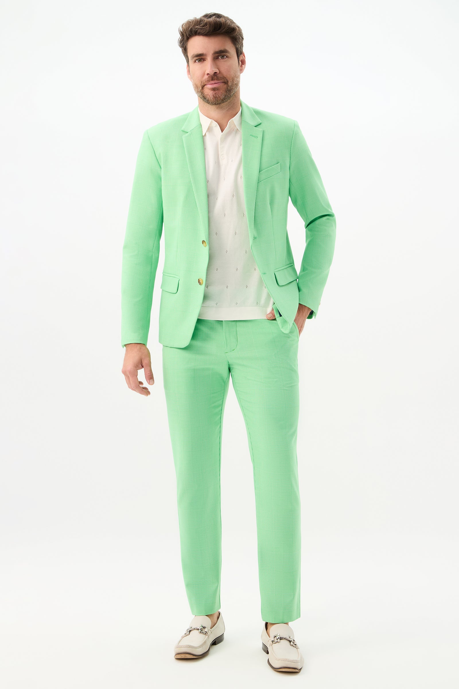 A man stands facing forward, wearing the Thurston Blazer - Game Time Glen Plaid with a white shirt and white shoes. The plain white background highlights the pastel green hue of the blazer.
