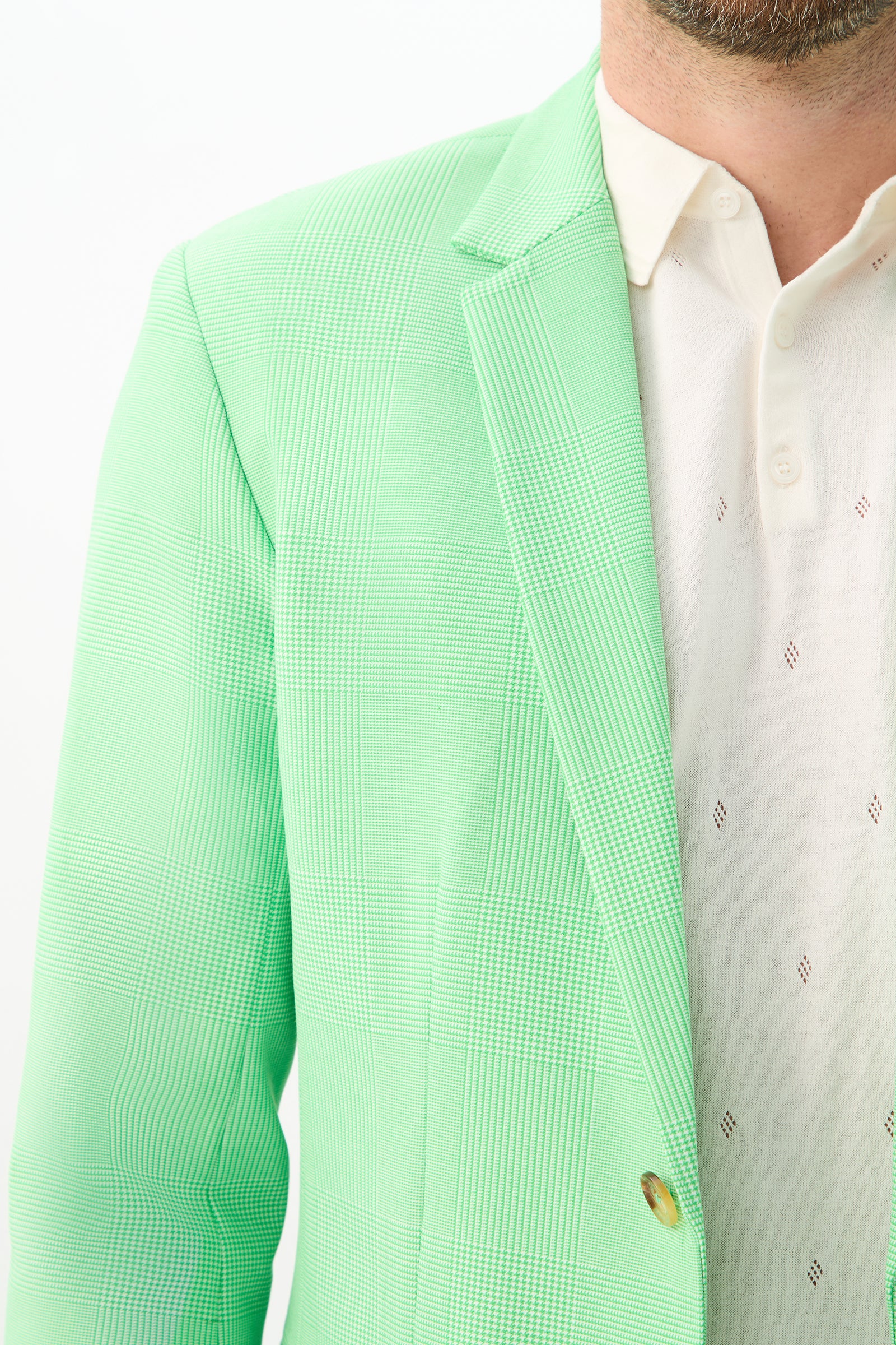 A close-up of a man wearing the Thurston Blazer - Game Time Glen Plaid over a white collared shirt with small diamond patterns, showing only part of his face, shoulder, and chest.