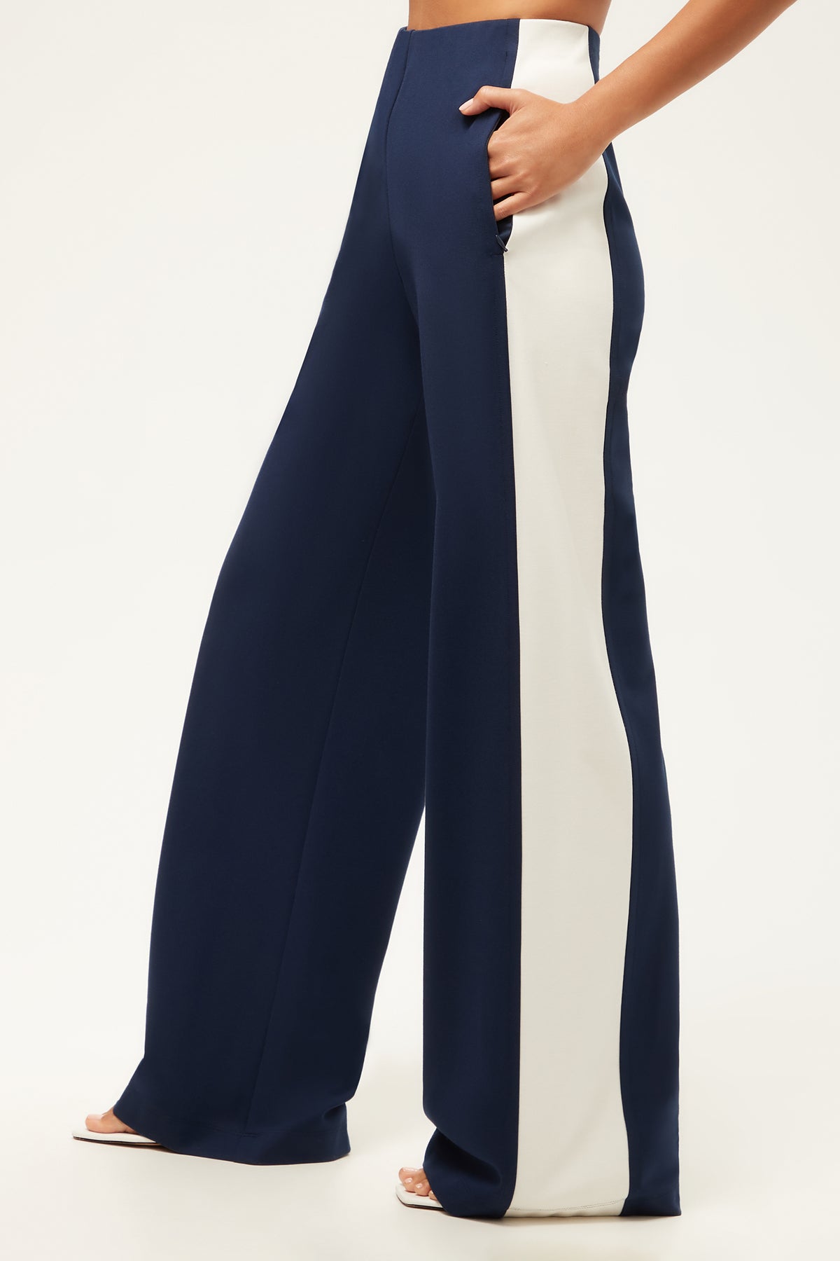 A person wearing the Record Wide-Leg Pant - Cozy Ponte in navy blue with vertical white side stripes, standing against a plain white background.