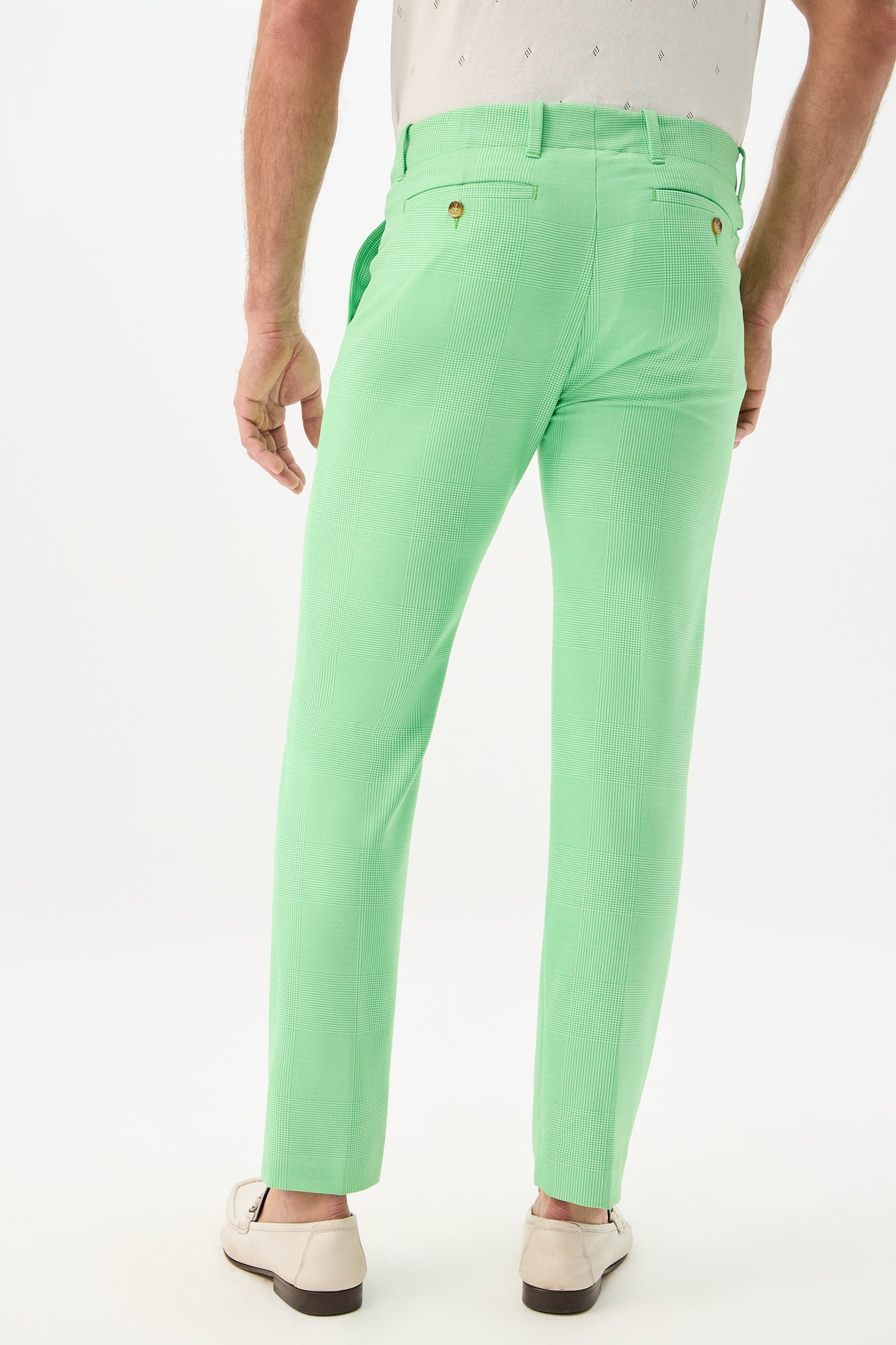 A man wearing the Alex Slim Trouser - Game Time Glen Plaid stands with his back to the camera, paired with a white patterned shirt and white loafers against a plain white background.