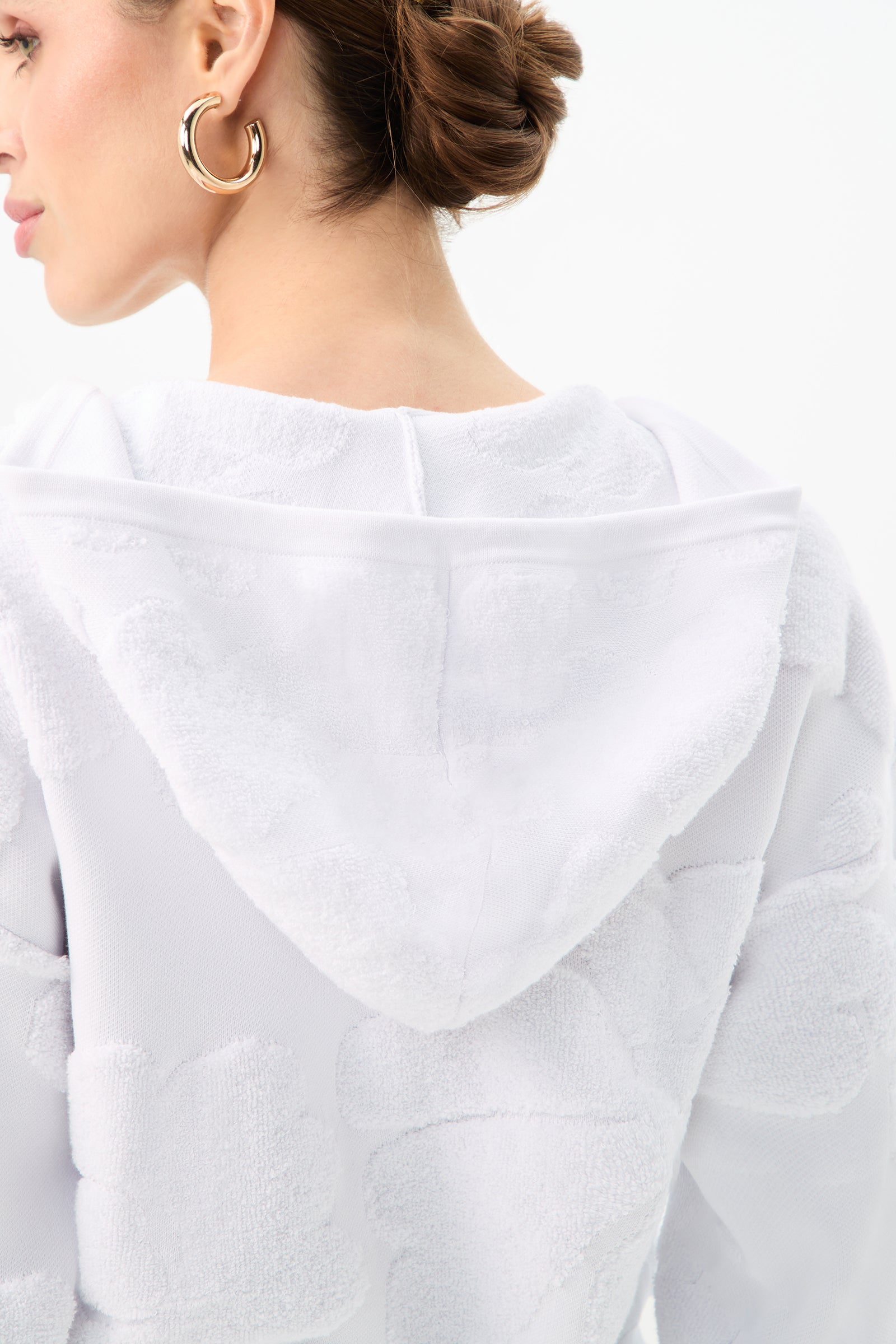 A woman with her hair in an updo and large gold hoop earrings wears the C.Z. Zip-Up Hoodie - Linsk Terry, shown from the back and side against a plain light background.