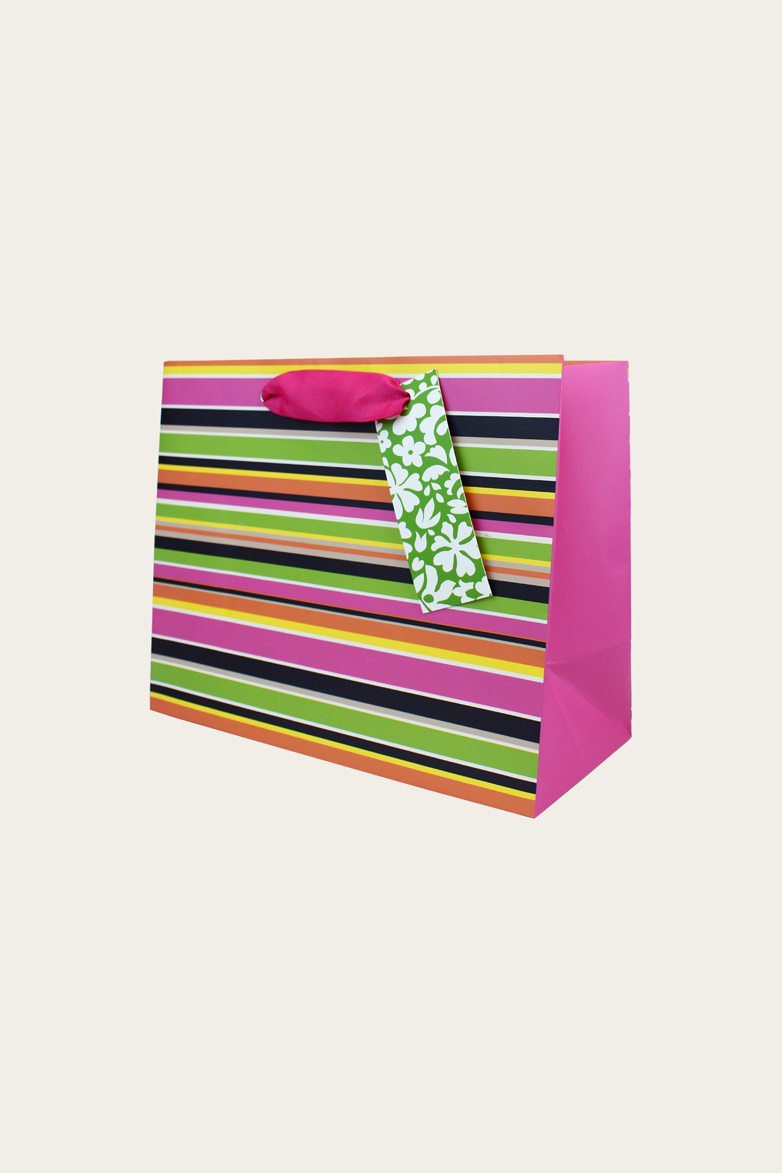 The TT Medium Gift Bag - Splash Stripe features horizontal stripes in pink, yellow, green, black, and orange, with pink ribbon handles and a green floral-patterned gift tag. Perfect for gifting on any occasion.