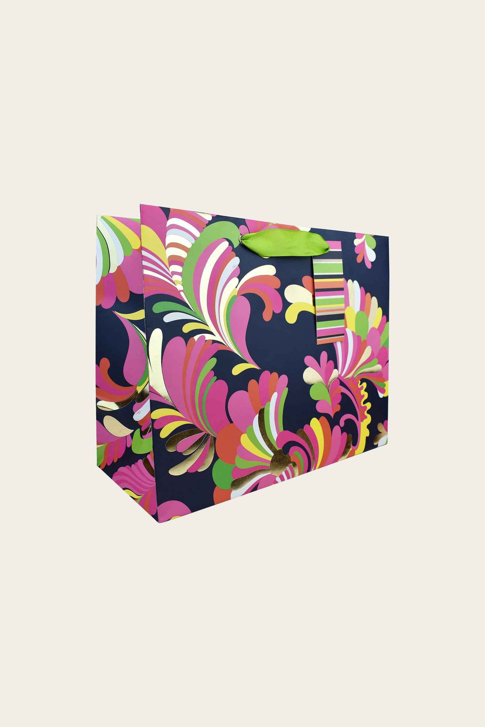 The TT Large Gift Bag - Palms Paradise features a vibrant swirling floral pattern in pink, green, yellow, and white on a dark background, with green ribbon handles and a matching gift tag.