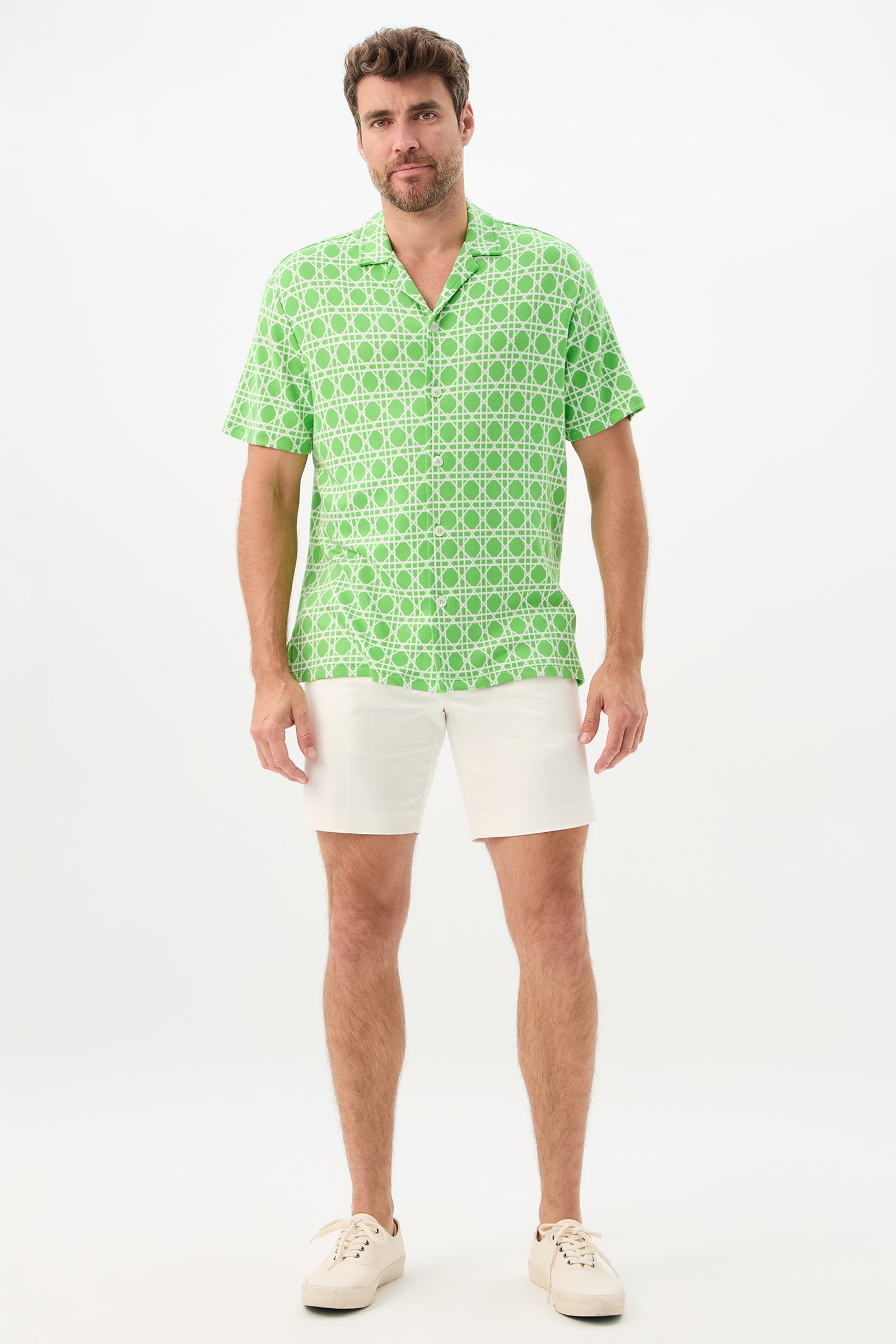 A man faces forward wearing the Felix Short-Sleeve Knit Shirt in Billie Jean, paired with white shorts and white sneakers, set against a plain white background.