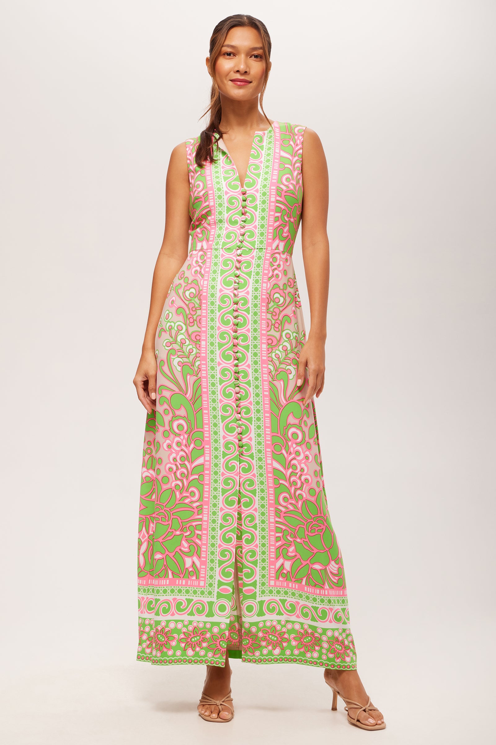 A woman stands against a plain white background wearing the Novak Sleeveless Midi Dress in Petra Floral and nude heeled sandals.