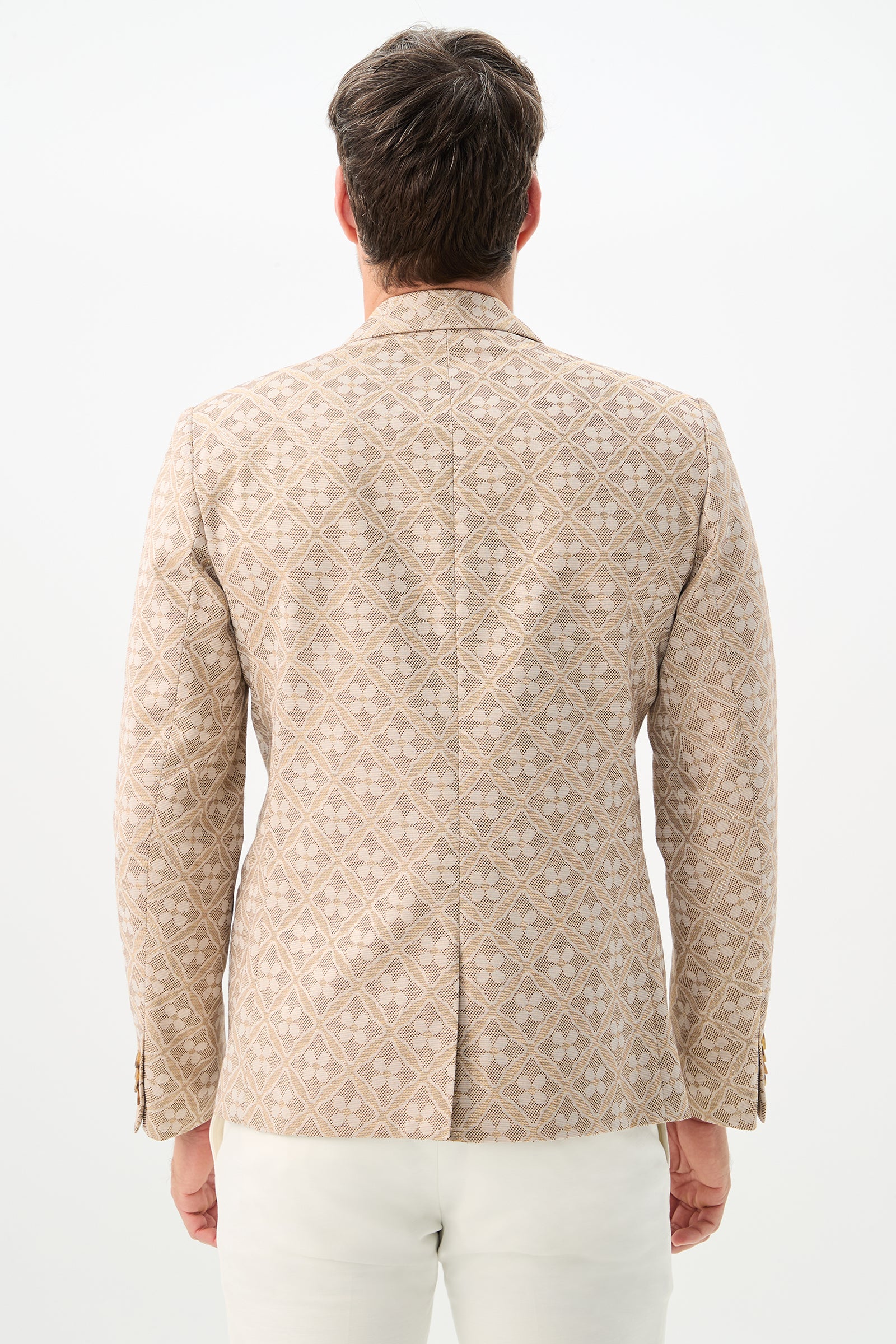 A man is seen from behind wearing the Thurston Blazer - Metallic Daisy Jacquard with white pants, standing against a plain white background.