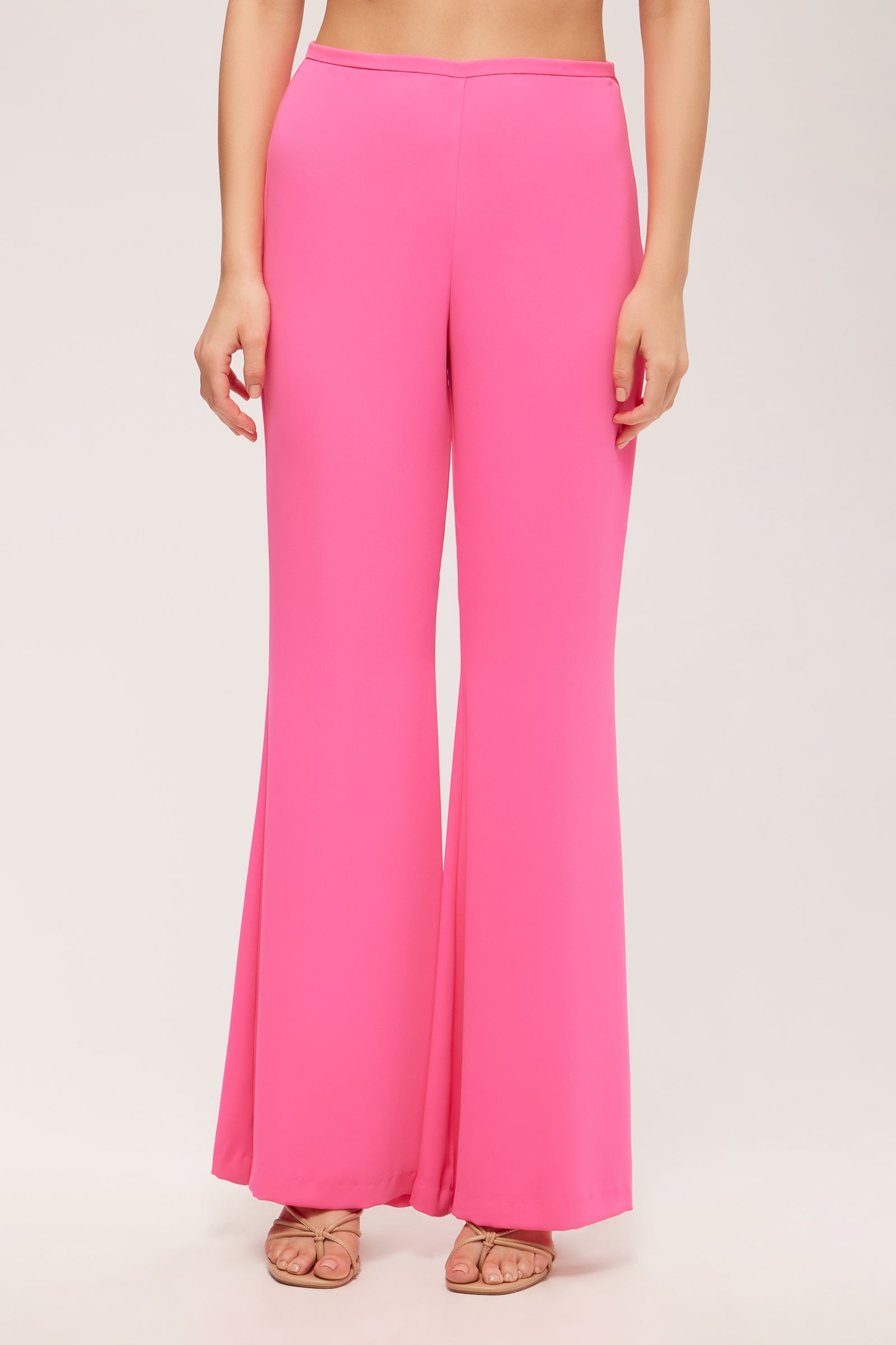 A person wearing Drop Shot Flared Pant - Double Georgette in Love All Pink with nude open-toe heels, standing against a plain light background.