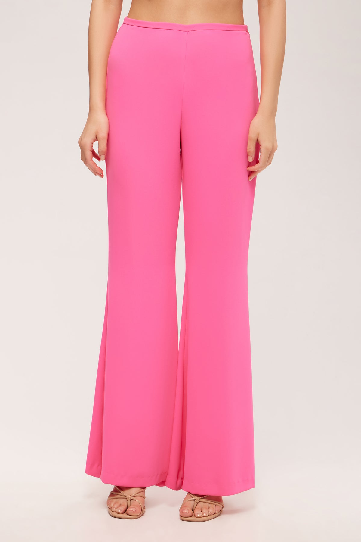 A person wearing Drop Shot Flared Pant - Double Georgette in Love All Pink with nude open-toe heels, standing against a plain light background.