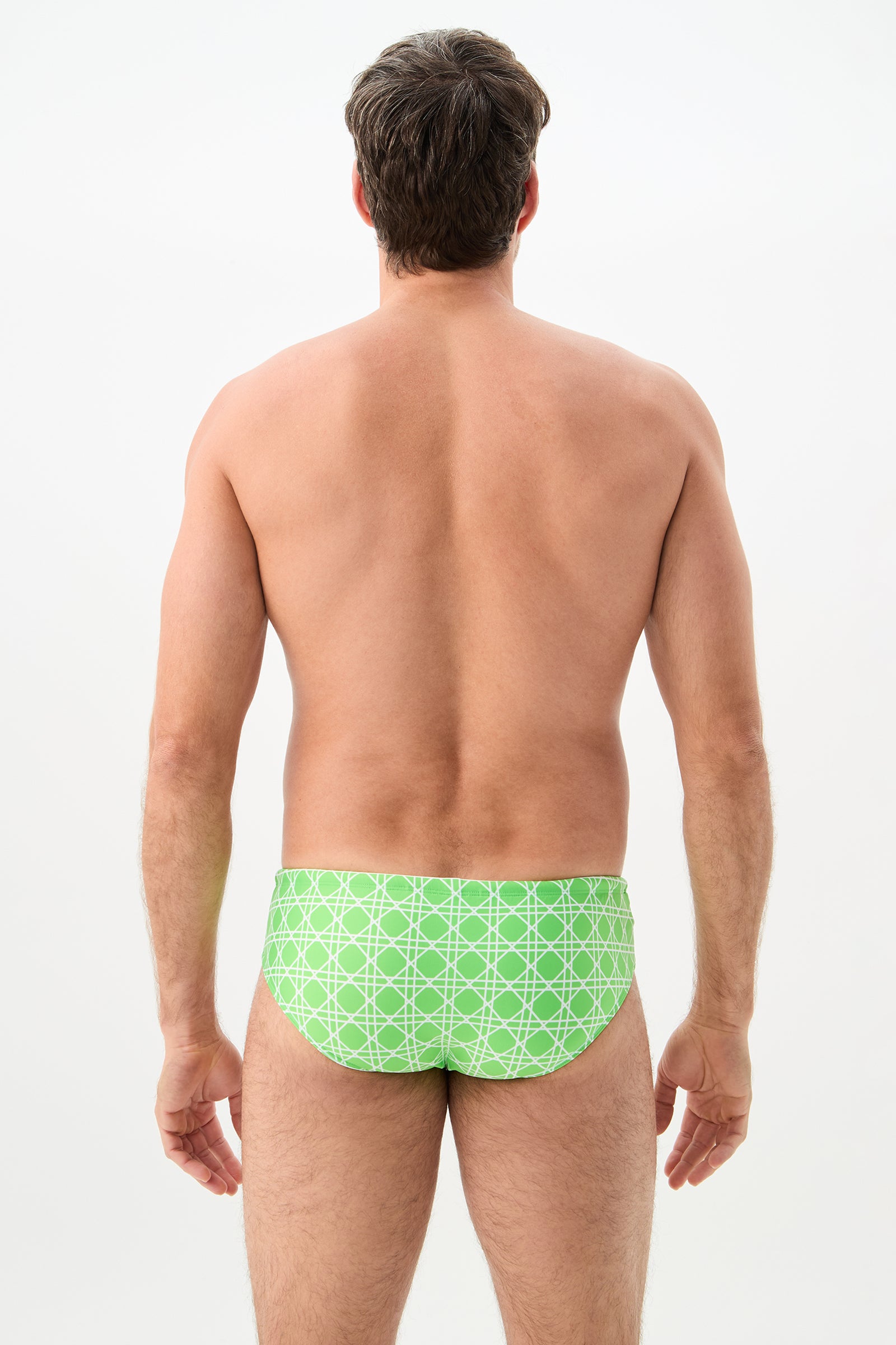 A man, shirtless and facing away from the camera against a plain light background, is wearing the Bondi Swim Brief - Billie Jean in a light green patterned design.