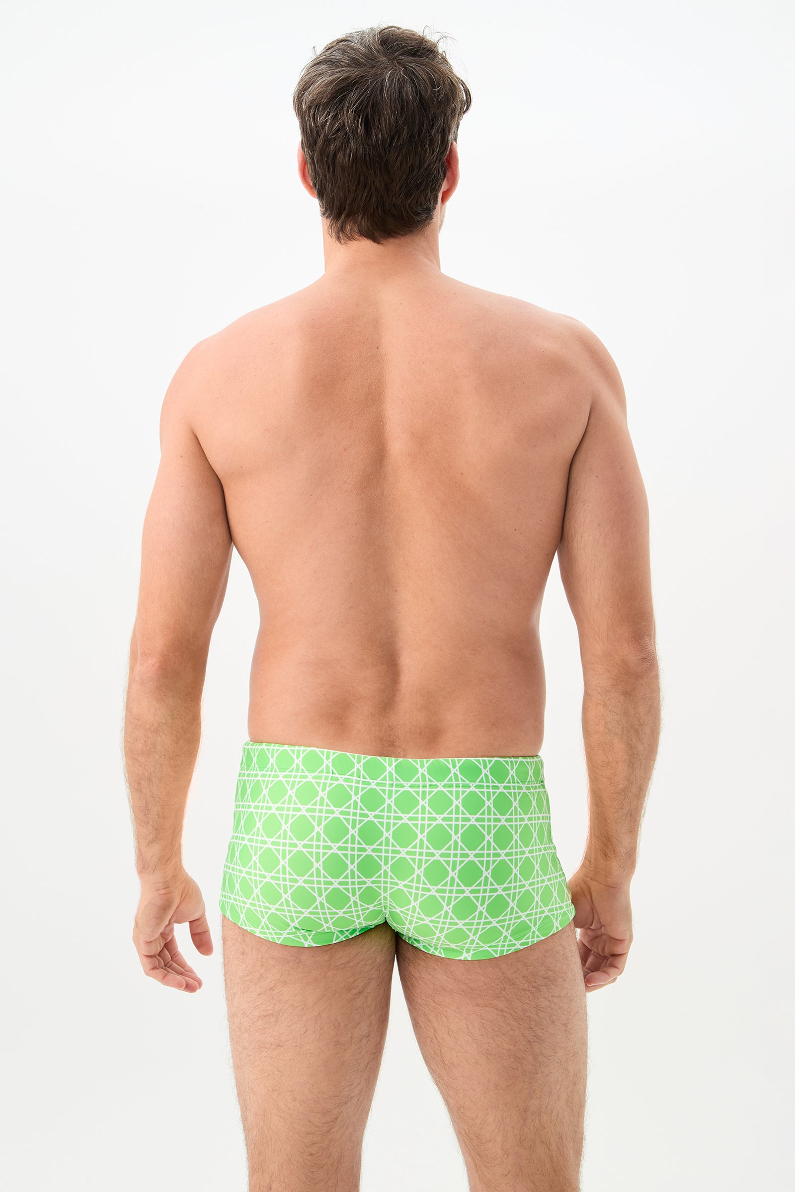 A man is standing with his back to the camera, wearing the Sorrento Swim Trunk - Billie Jean. The background is plain white.