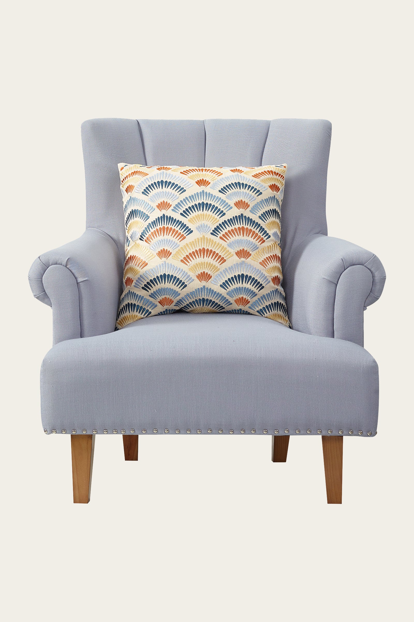 A light gray upholstered armchair with wooden legs features the Pasadena Embroidered Euro Throw Pillow - Terra, showcasing a colorful geometric fan pattern in blue, orange, and yellow at the center of the chair.