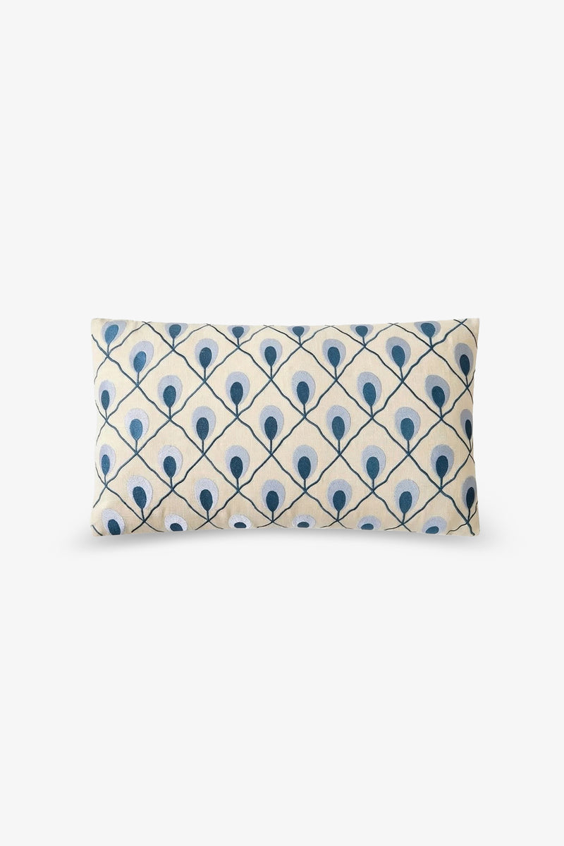 Roseville Embroidered Lumbar Pillow featuring a cream background and a repeating pattern of blue dots and lines forming a diamond lattice design reminiscent of stylized peacock feathers.