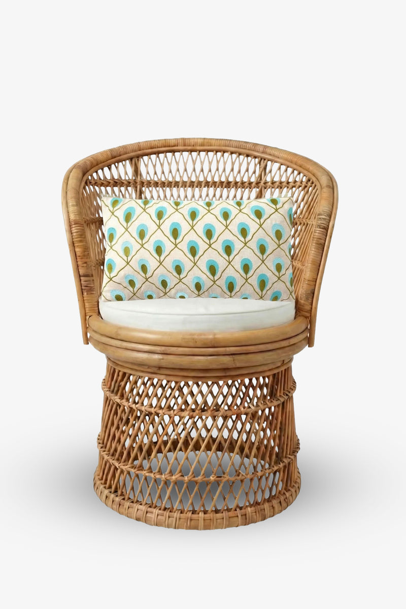 Round rattan chair with an open woven design, featuring a circular cushion and the Roseville Embroidered Lumbar Pillow—adorned with a colorful peacock feather pattern—set against a plain white background.