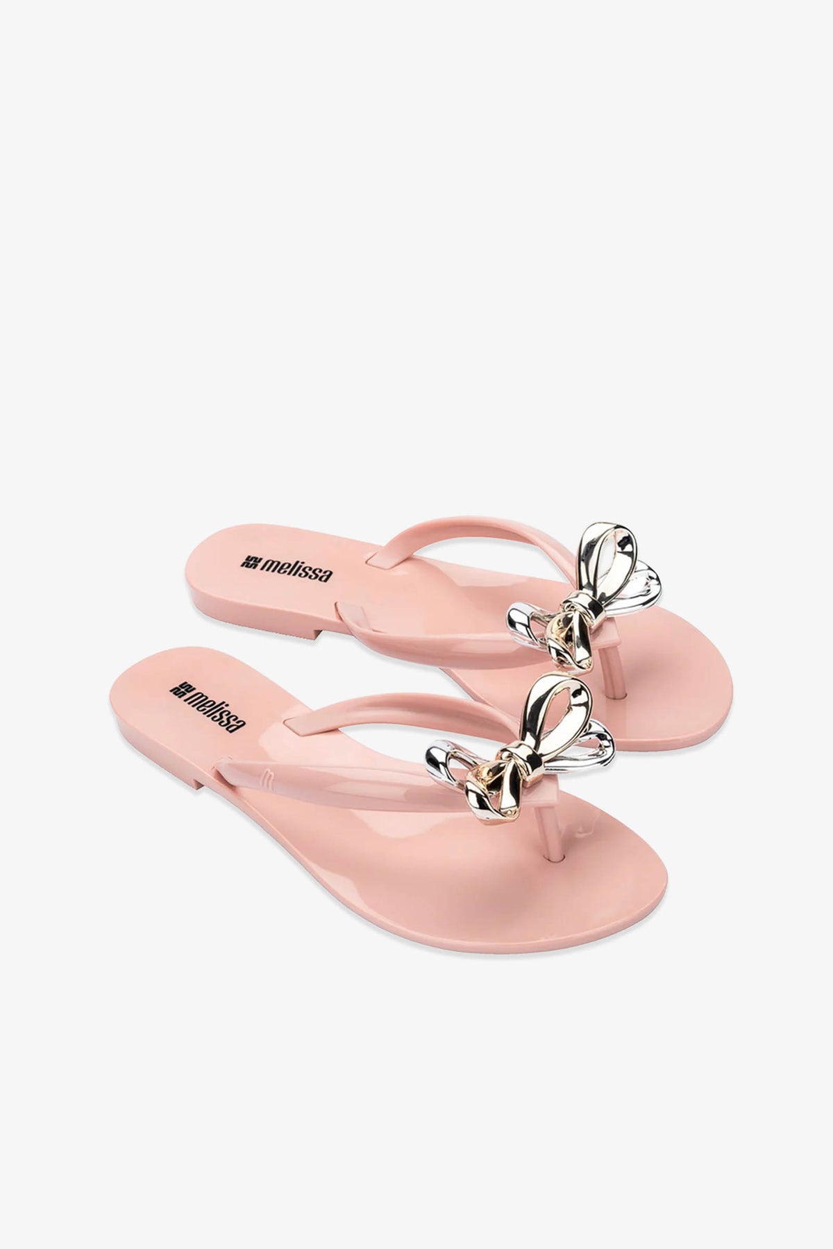 The Melissa Harmonic Eclipse Bow Sandal in pink features thong straps adorned with shiny metallic butterfly ornaments, shown against a white background.