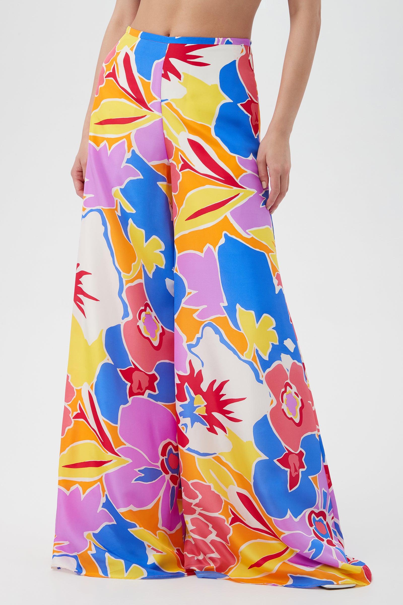 A person wears the Jack Wide-Leg Pant in Soie Paradis, featuring a colorful floral pattern. Their torso is mostly out of frame, set against a plain white background.