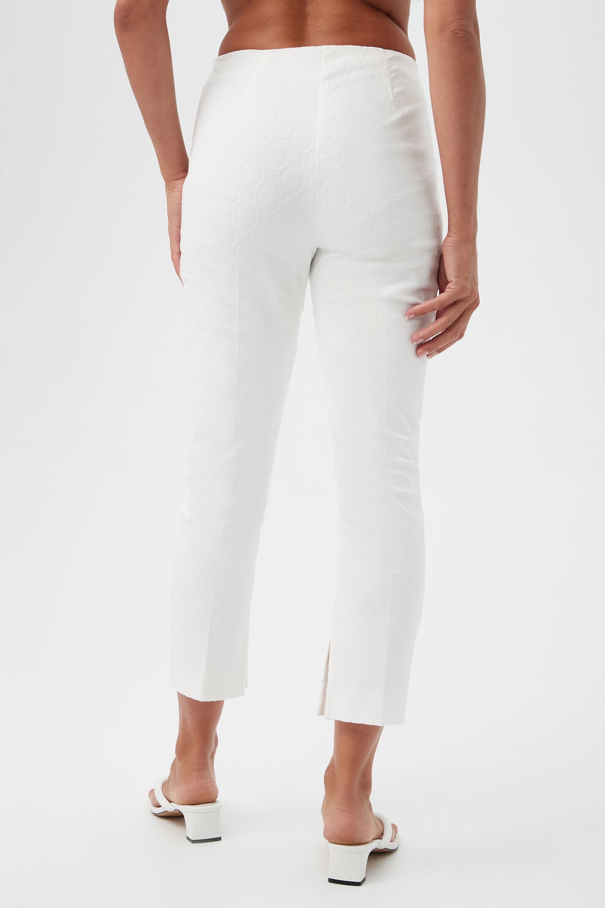 Wearing Pop Slim-Leg Stretch Pants in white and white heeled sandals, the person is shown from the back against a plain white background.