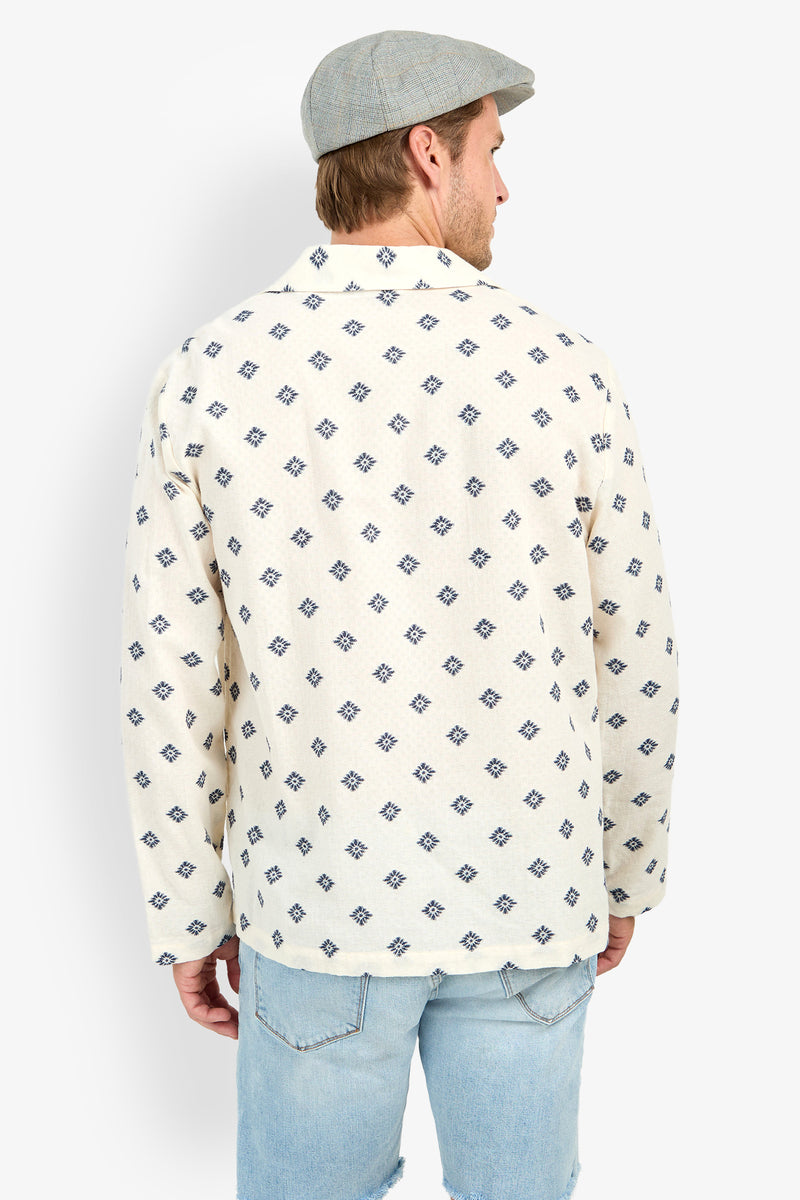 A person stands with their back to the camera against a white background, wearing a gray flat cap, Hendrix Long-Sleeve Pullover, and light blue ripped jeans.