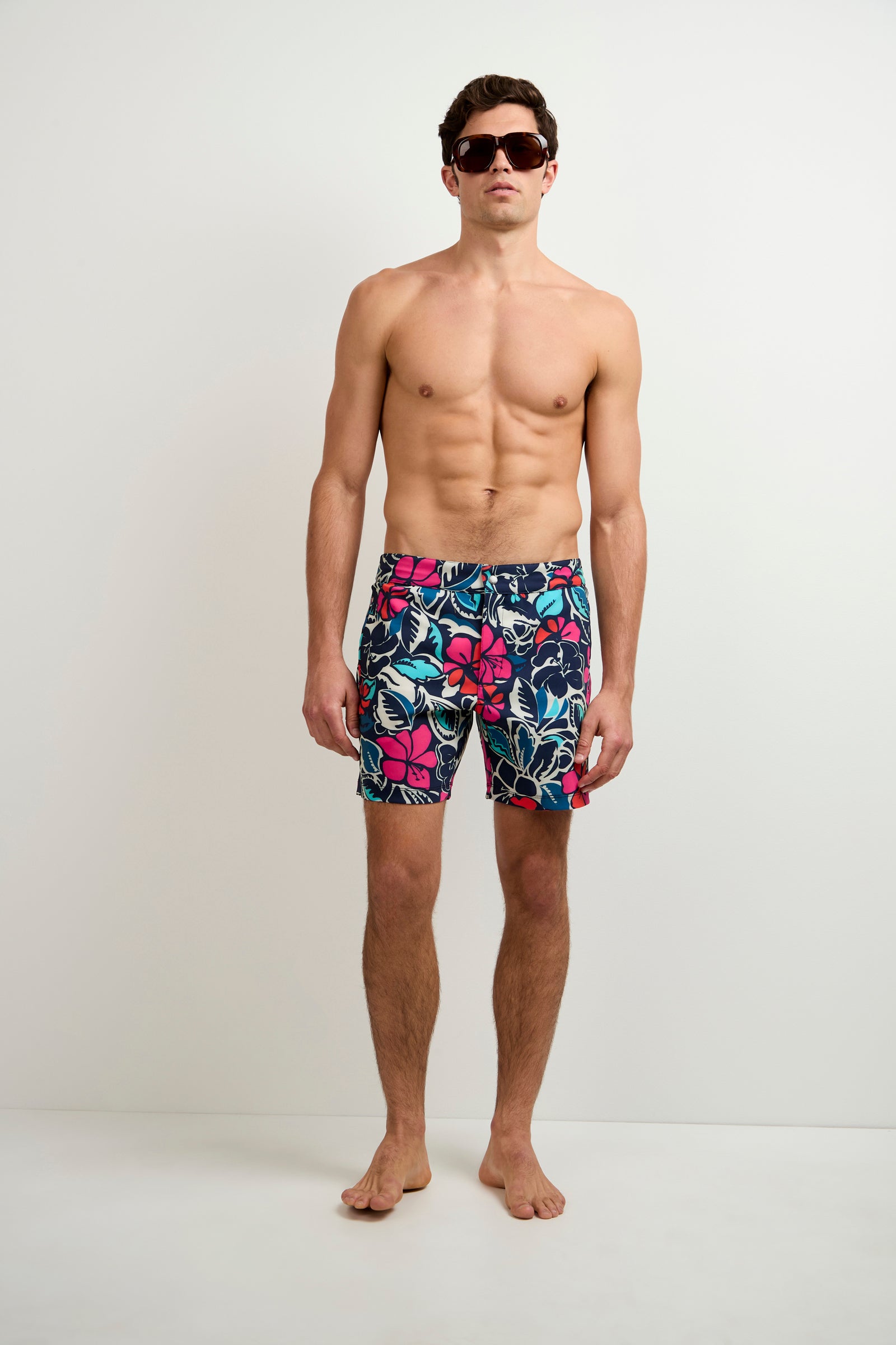 A man wearing the Honolulu Board Short - Copacabana stands barefoot and shirtless against a plain white background, looking straight at the camera with dark sunglasses.