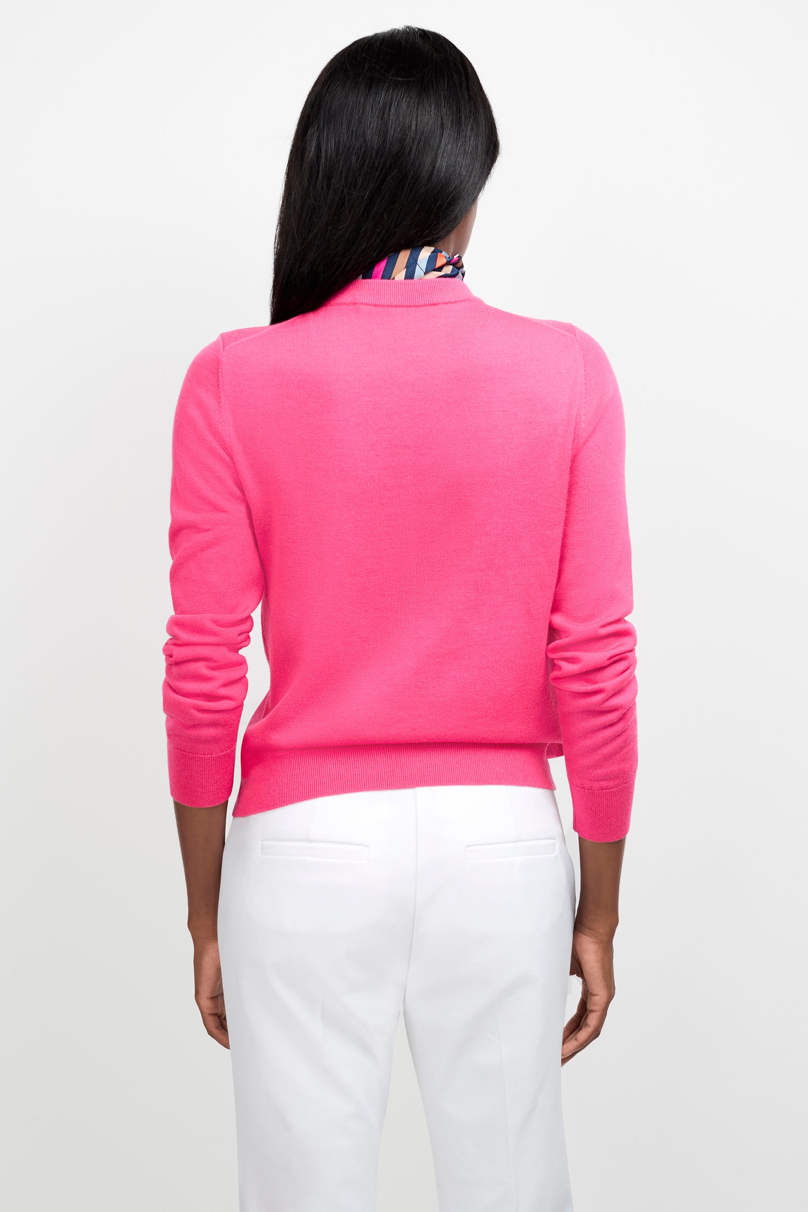 A person with long dark hair is wearing the Old Fashioned Sweater in bright pink and white pants, standing with their back to the camera against a plain white background.