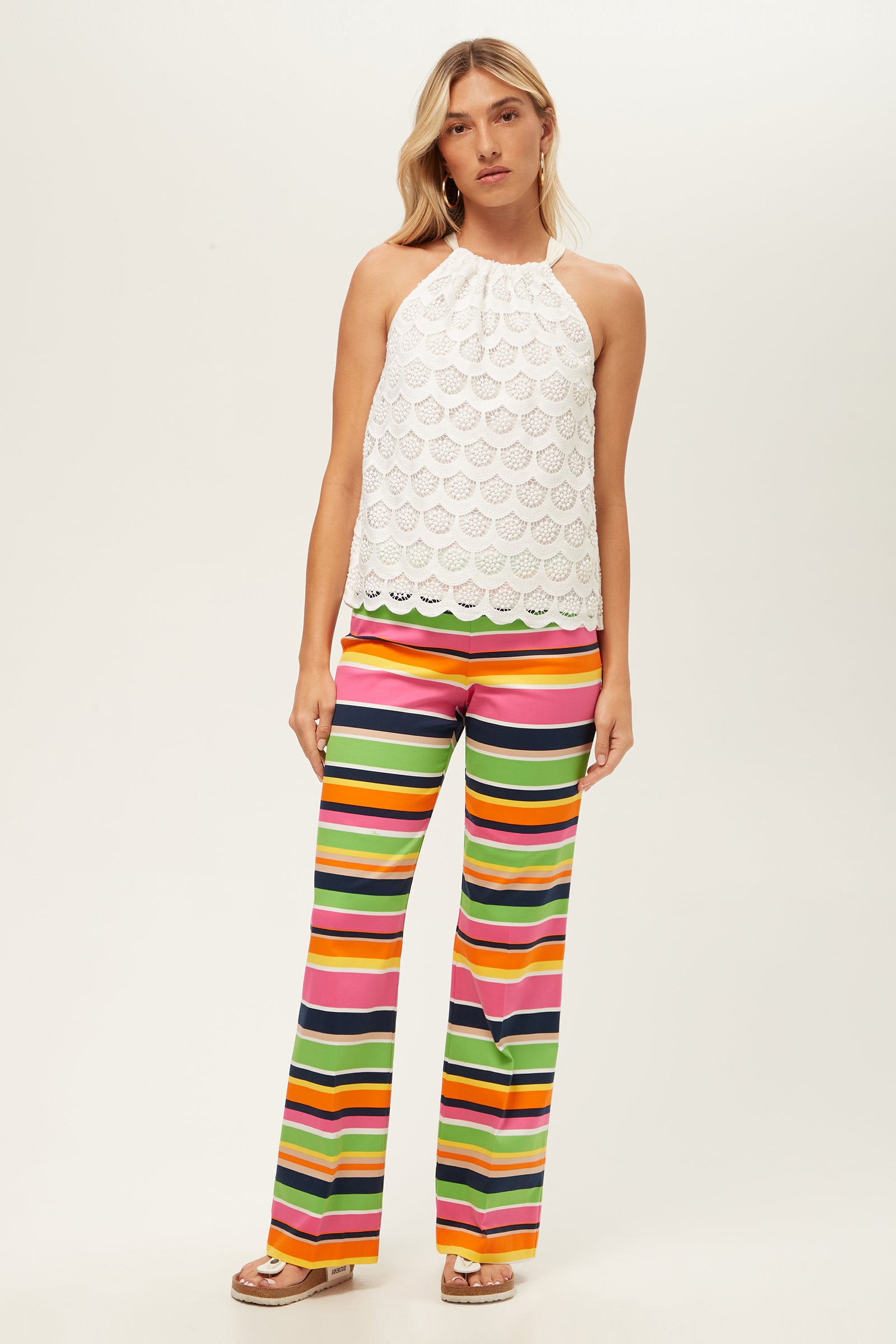 A person wears Rudi Straight-Leg Pant in Splash Stripe with a white halter-neck lace top, standing against a plain light background and looking at the camera.