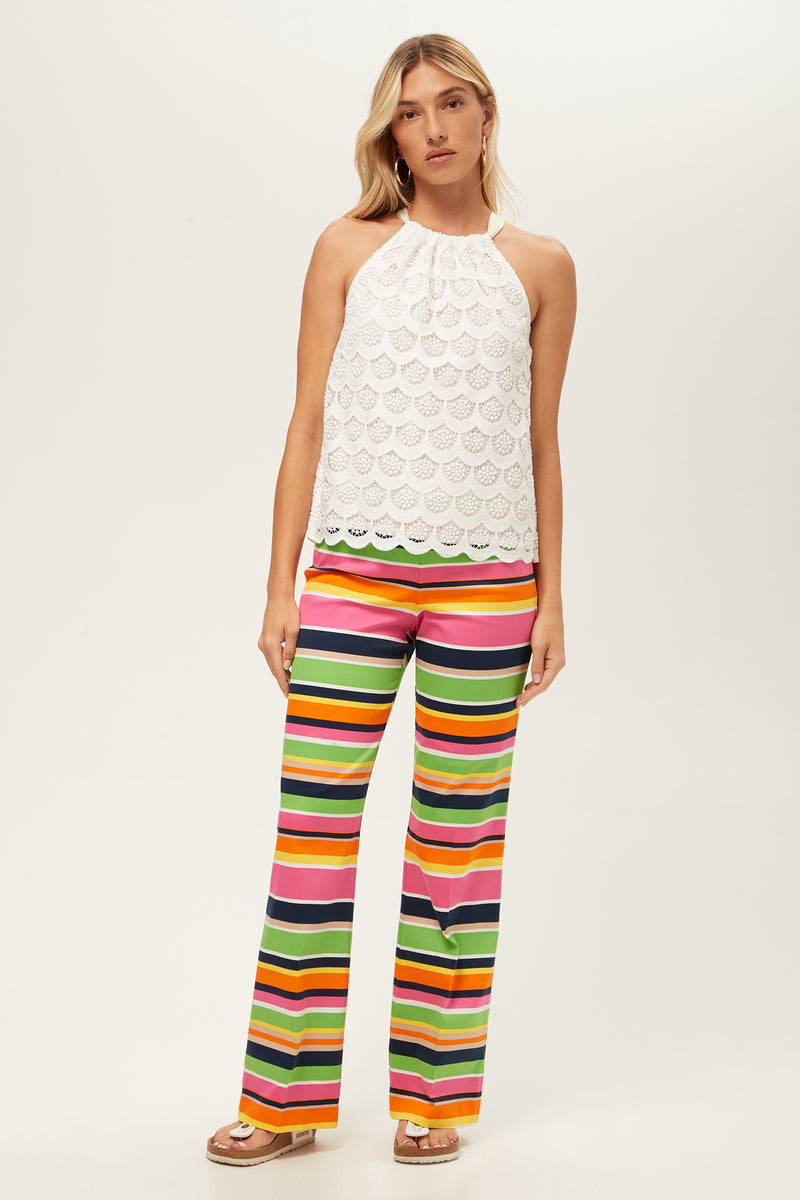 A person wears Rudi Straight-Leg Pant in Splash Stripe with a white halter-neck lace top, standing against a plain light background and looking at the camera.