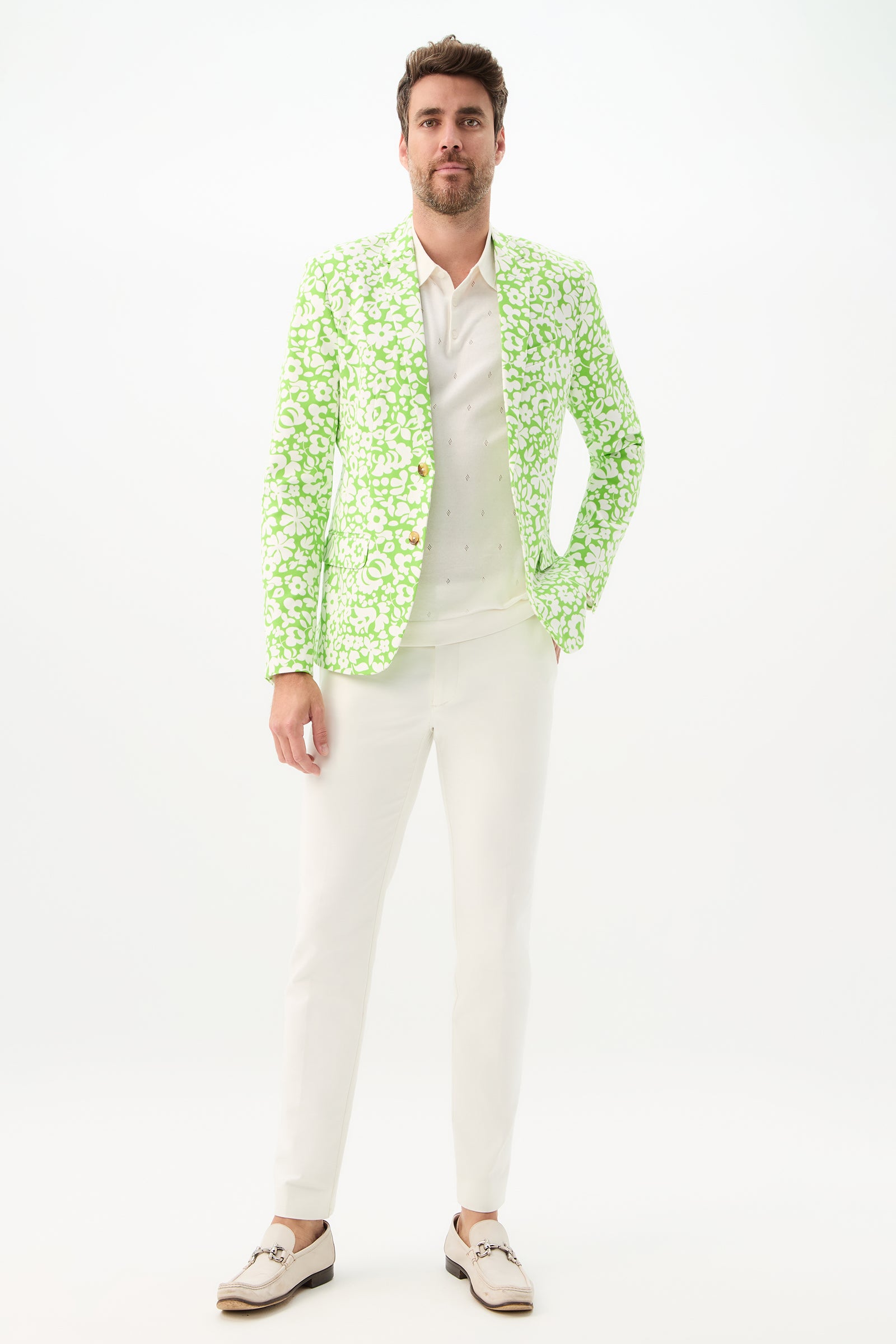 A man with short brown hair and a trimmed beard stands against a white background wearing the Thurston Blazer - Poolside Gossip over a white shirt and pants, paired with white loafers.
