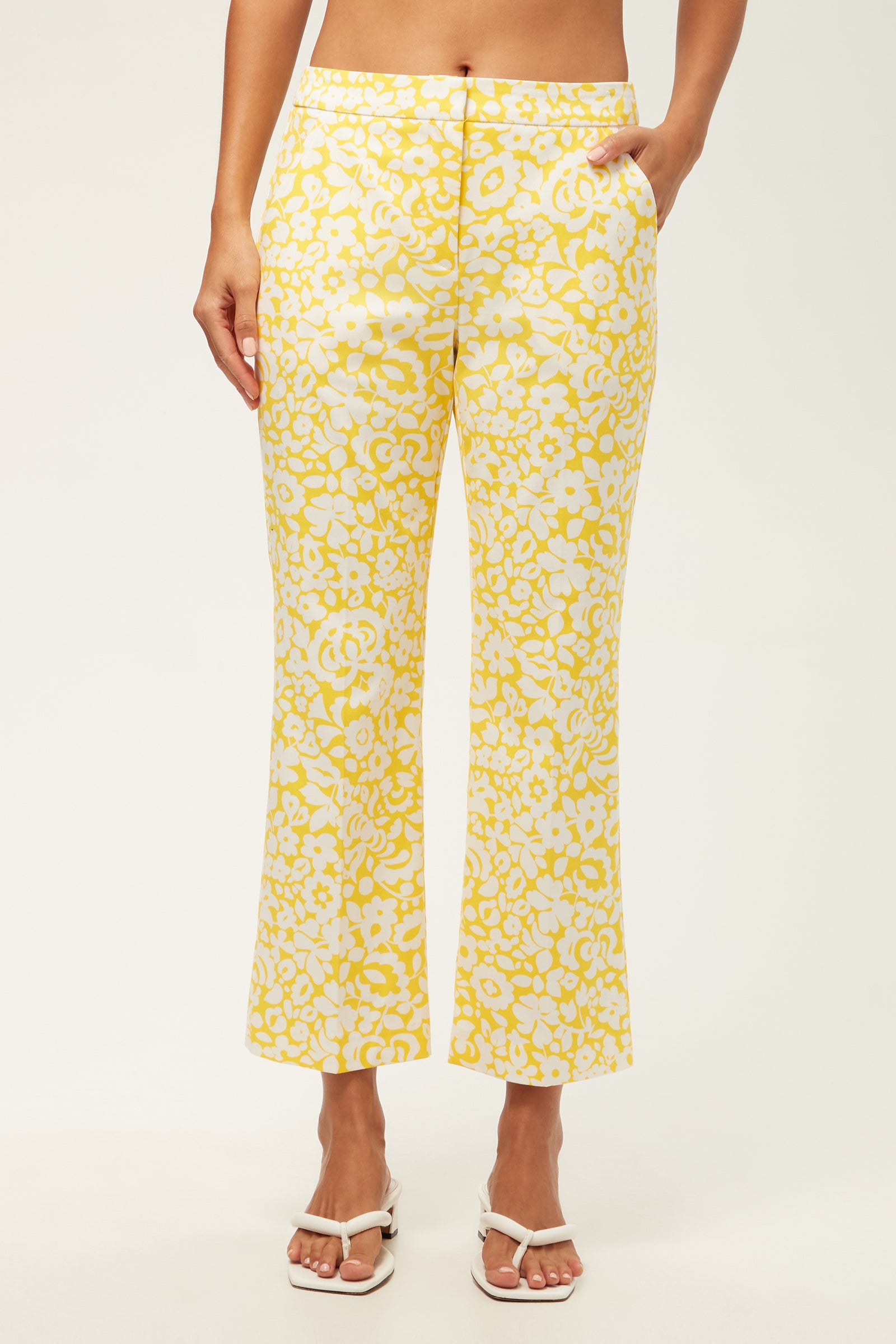 Wearing the Lulu Cropped Pant - Poolside Gossip in Desert Sun, a person stands with hands in pockets, paired with white sandals against a plain background.