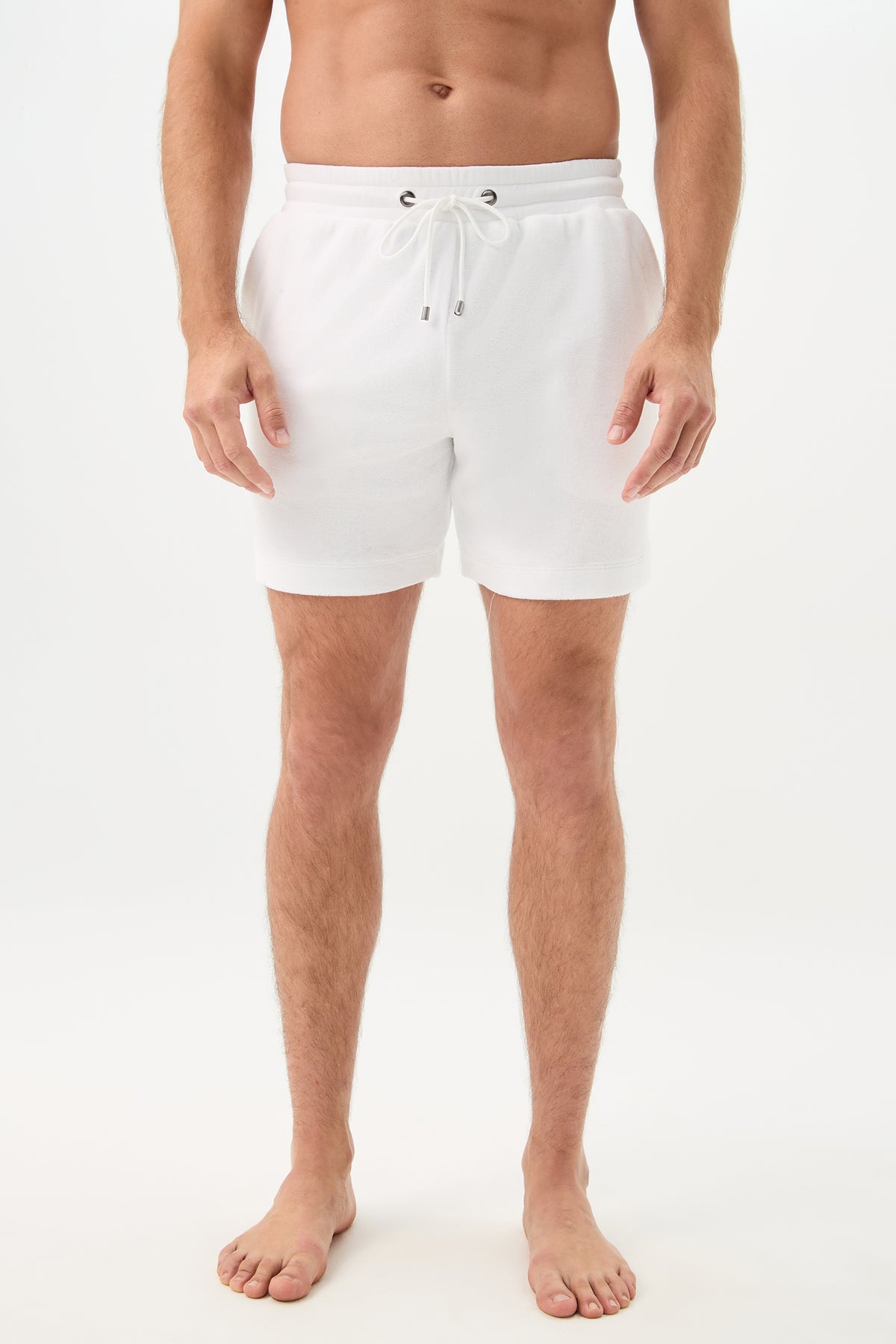 A man stands barefoot against a plain white background, arms relaxed at his sides, wearing the Lounge Knit Short - Linsk Terry in white. The image is cropped from his chest to his feet.