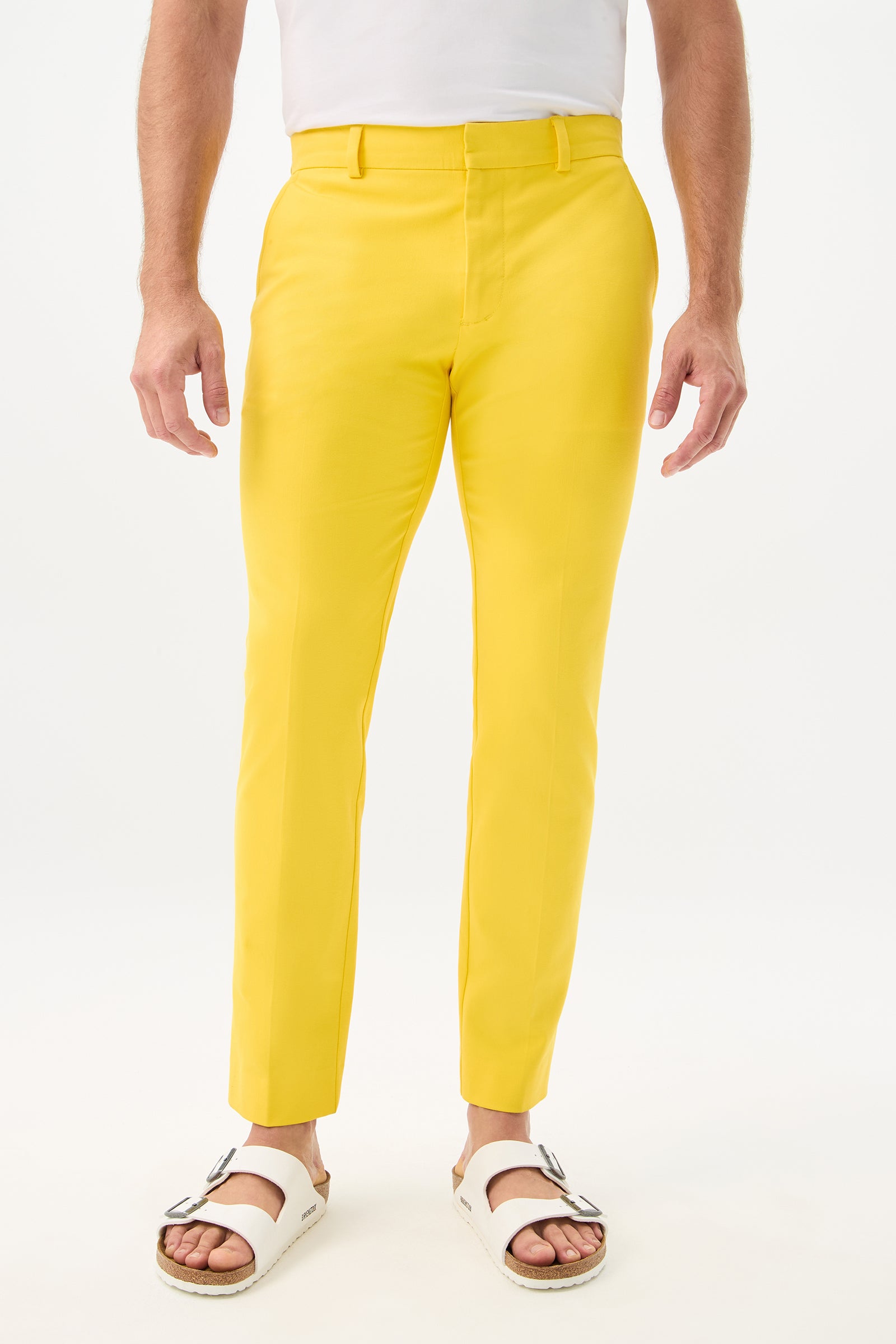A person models the Clyde Slim Trouser - Sunset Stretch in Lemon, with only their lower torso and legs visible against a plain white background.