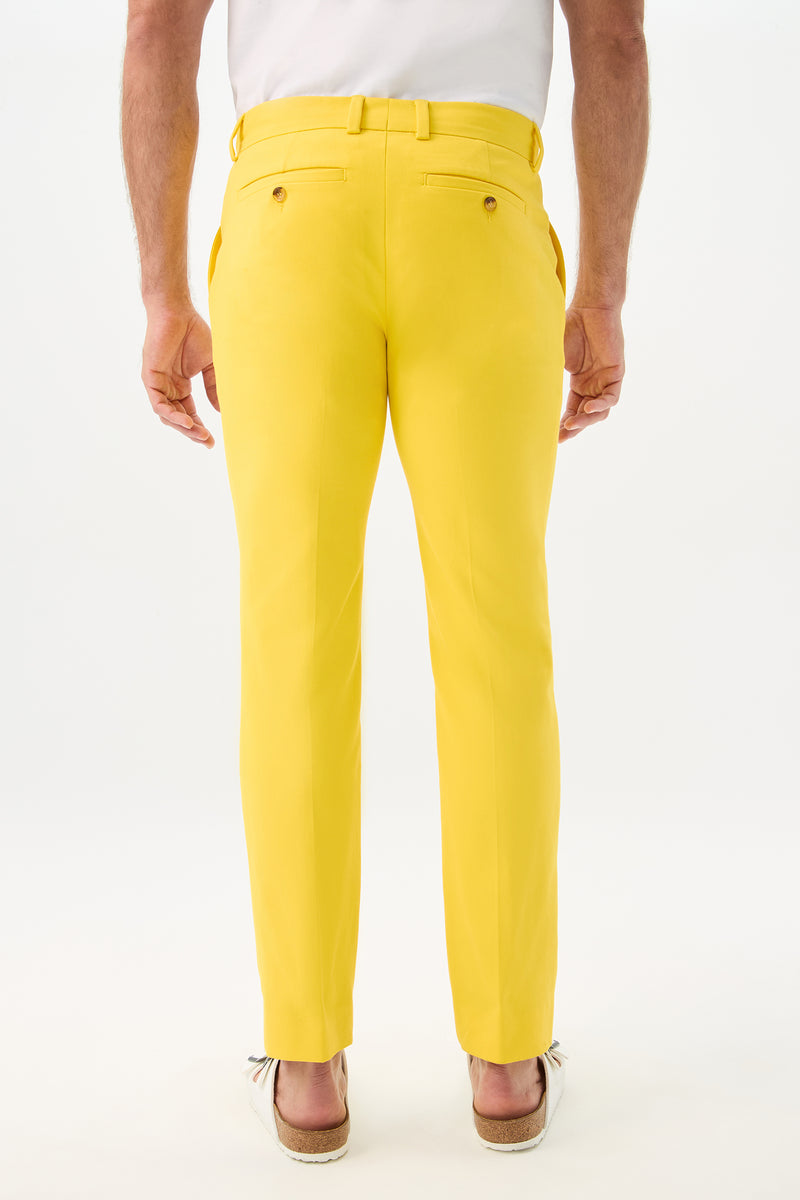 A person stands with their back to the camera against a plain white background, wearing Clyde Slim Trouser - Sunset Stretch and light-colored shoes.