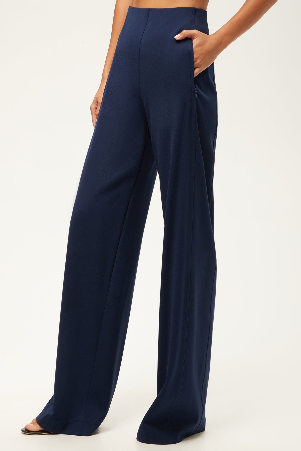 A person wearing the Record Essential Wide-Leg Pant - Cozy Ponte in Ink, with one hand in a pocket, stands against a plain light background.