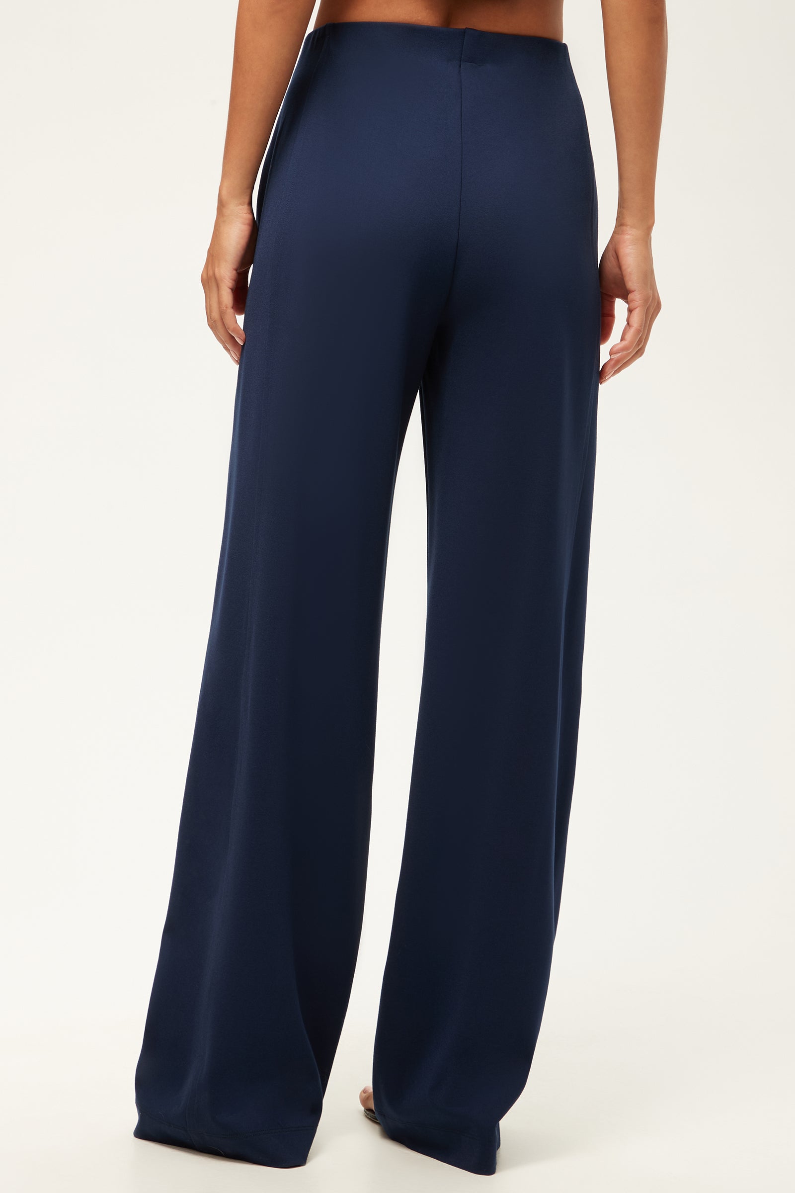 A person stands barefoot in the Record Essential Wide-Leg Pant - Cozy Ponte, featuring a high-waisted, wide-leg silhouette in navy blue. The back view is shown against a plain light background.