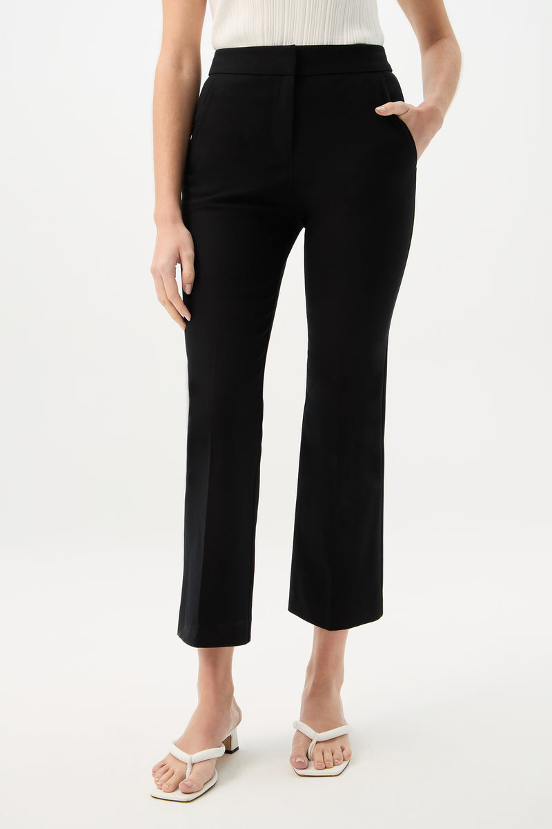 A person wearing Lulu Cropped Pant - Cotton Bi-Stretch in black and white heeled sandals stands against a plain white background, with their left hand in their pocket and their top partially visible.