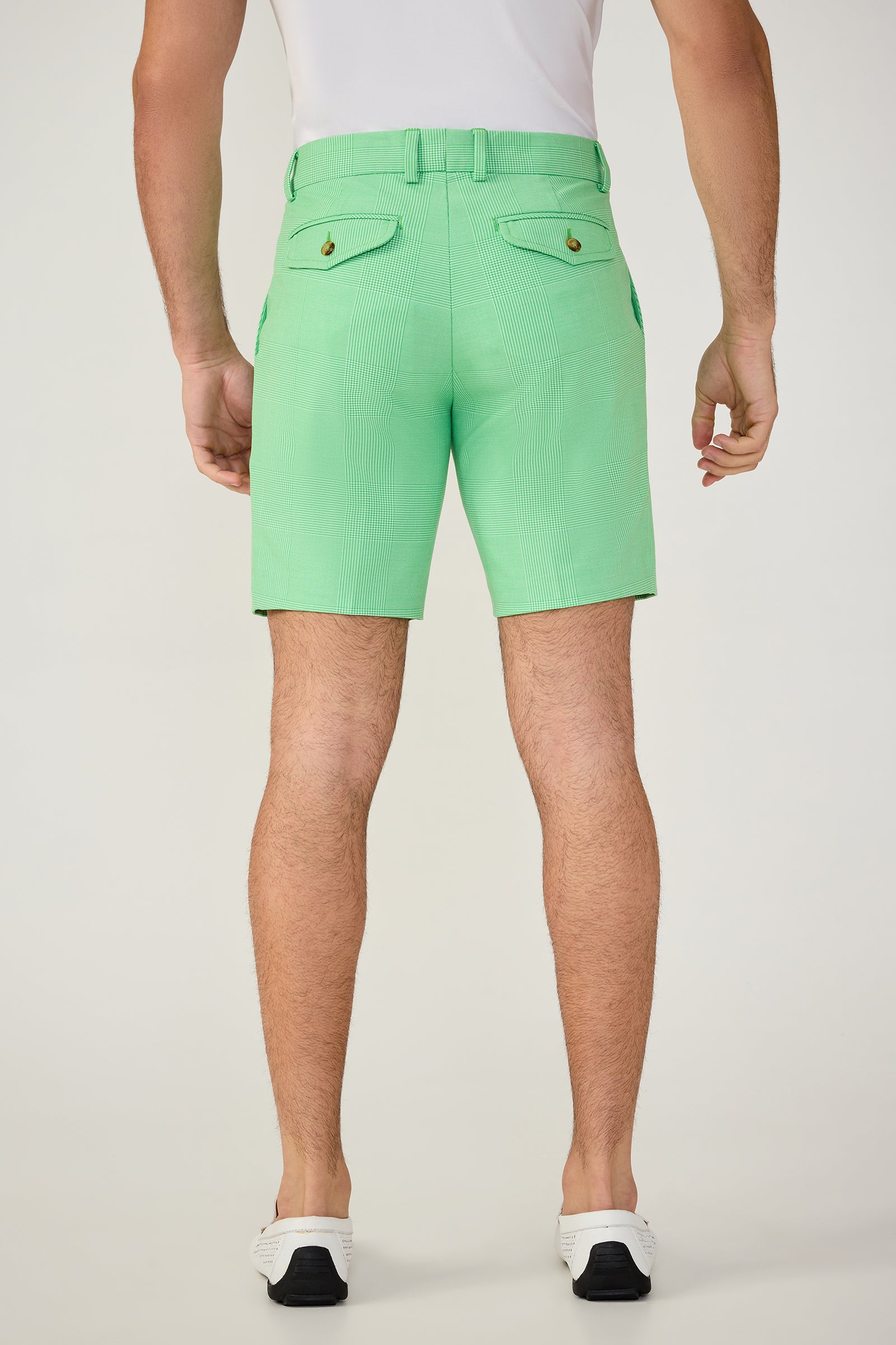 A man is seen from behind wearing the Travis Short - Game Time Glen Plaid in light green, paired with a white shirt and white sneakers with black soles, standing against a plain light background.