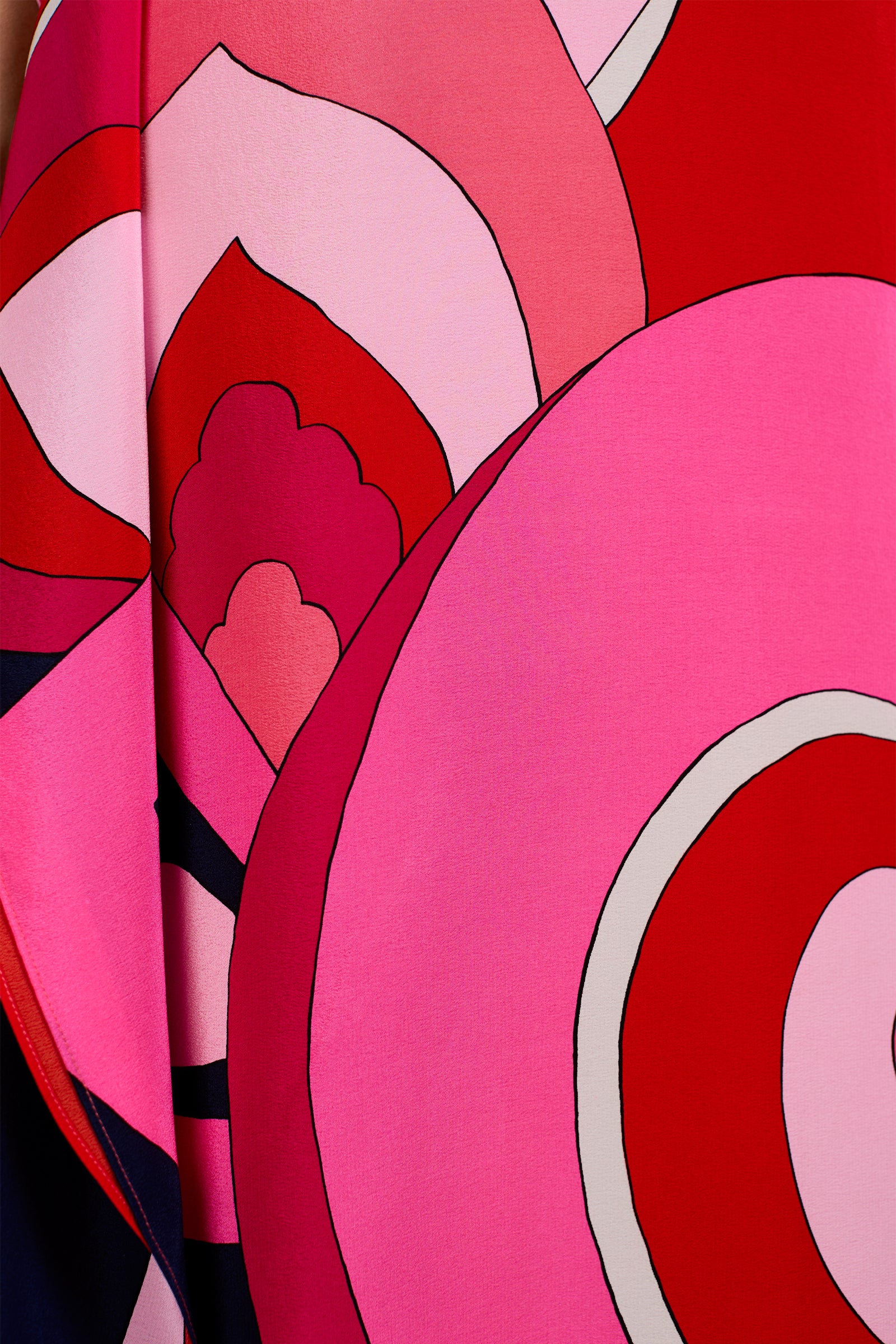 Close-up of the Jalani Maxi Caftan Dress fabric, showcasing bold abstract patterns in pink, red, and cream with circular and floral shapes outlined in black.