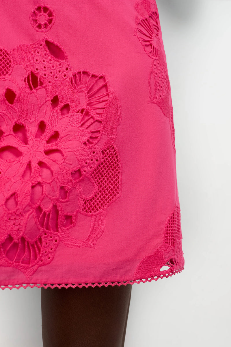 Close-up of the Francesca Shift Dress in bright pink, showcasing bold floral cut-out embroidery and lace hem details, worn by a person with dark skin.