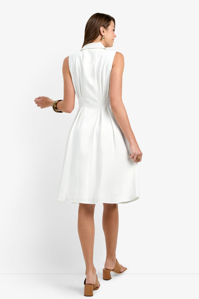 Woman with brown hair stands with her back to the camera, wearing the Farfalla Sleeveless Midi Dress—white, fitted at the waist with a flared knee-length skirt—paired with tan heeled sandals, gold earrings, and a bracelet.