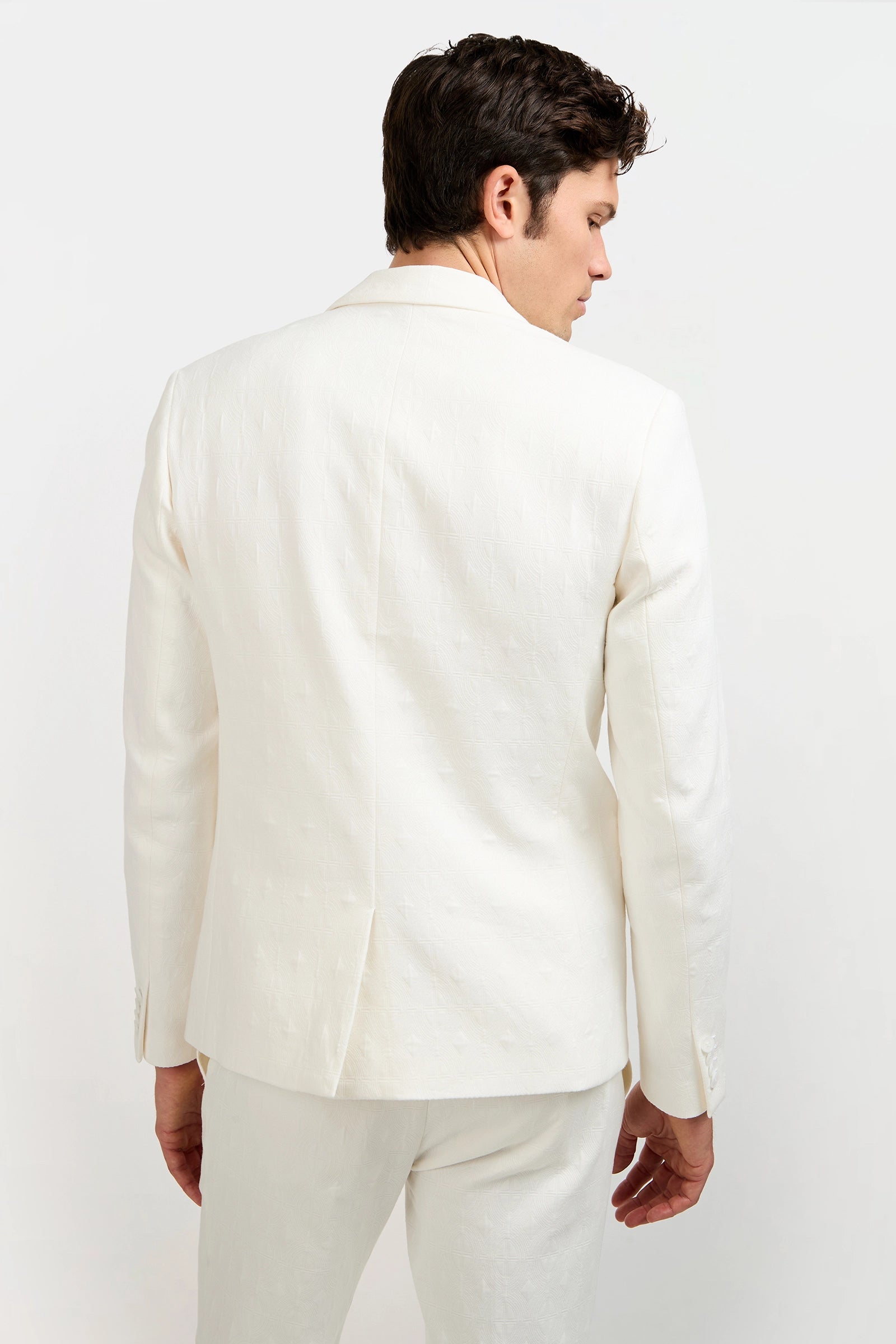 A man with dark hair is seen from behind wearing the Thurston Blazer in Tegola Textured Jacquard, along with matching pants, set against a plain white background.
